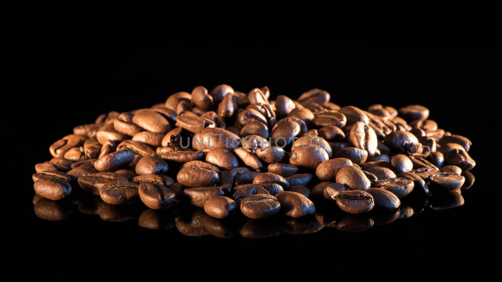 Coffee beans on a black mirror background close-up.