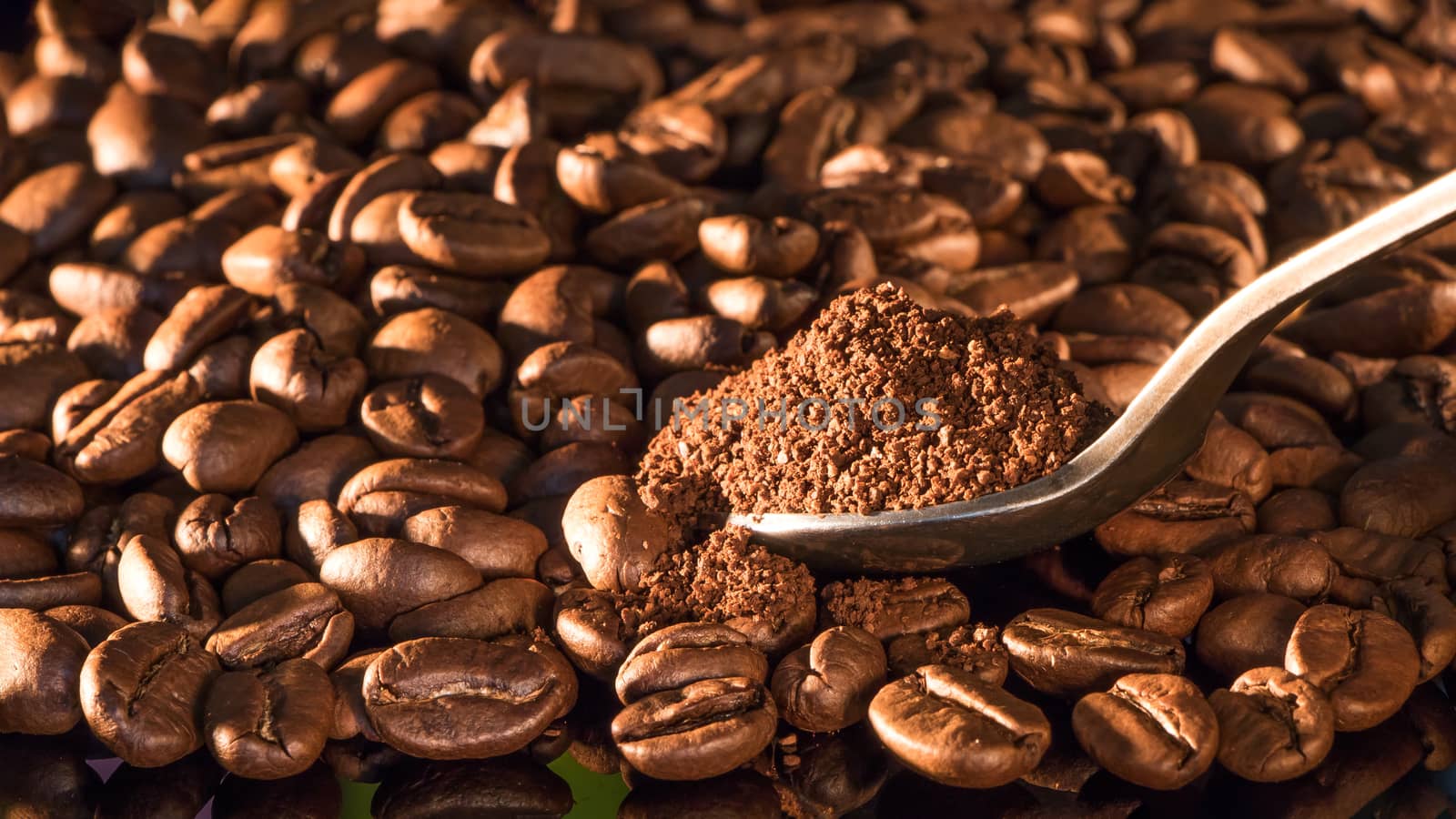 Coffee beans close-up with a spoon of ground coffee on a mirror  by YevgeniySam