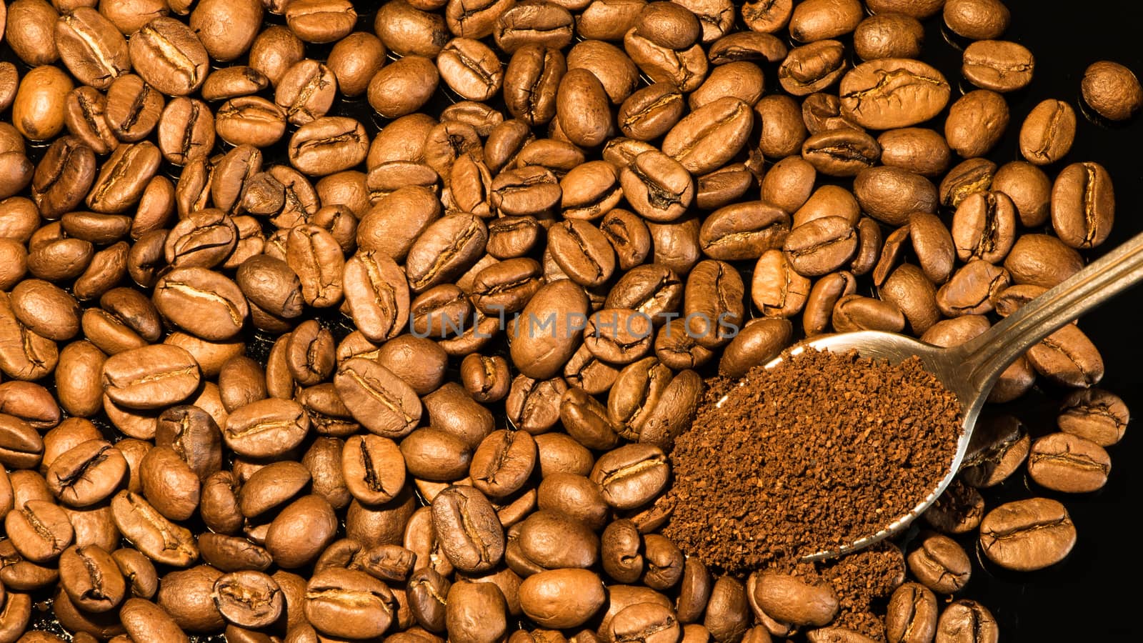 Coffee beans close-up with a spoon of ground coffee on a mirror  by YevgeniySam