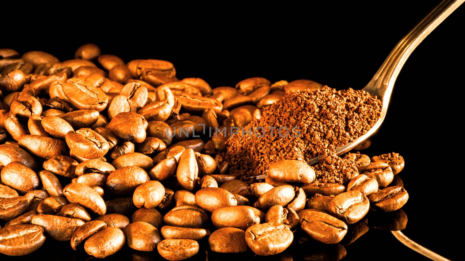 Coffee beans close-up with a spoon of ground coffee on a mirror background.