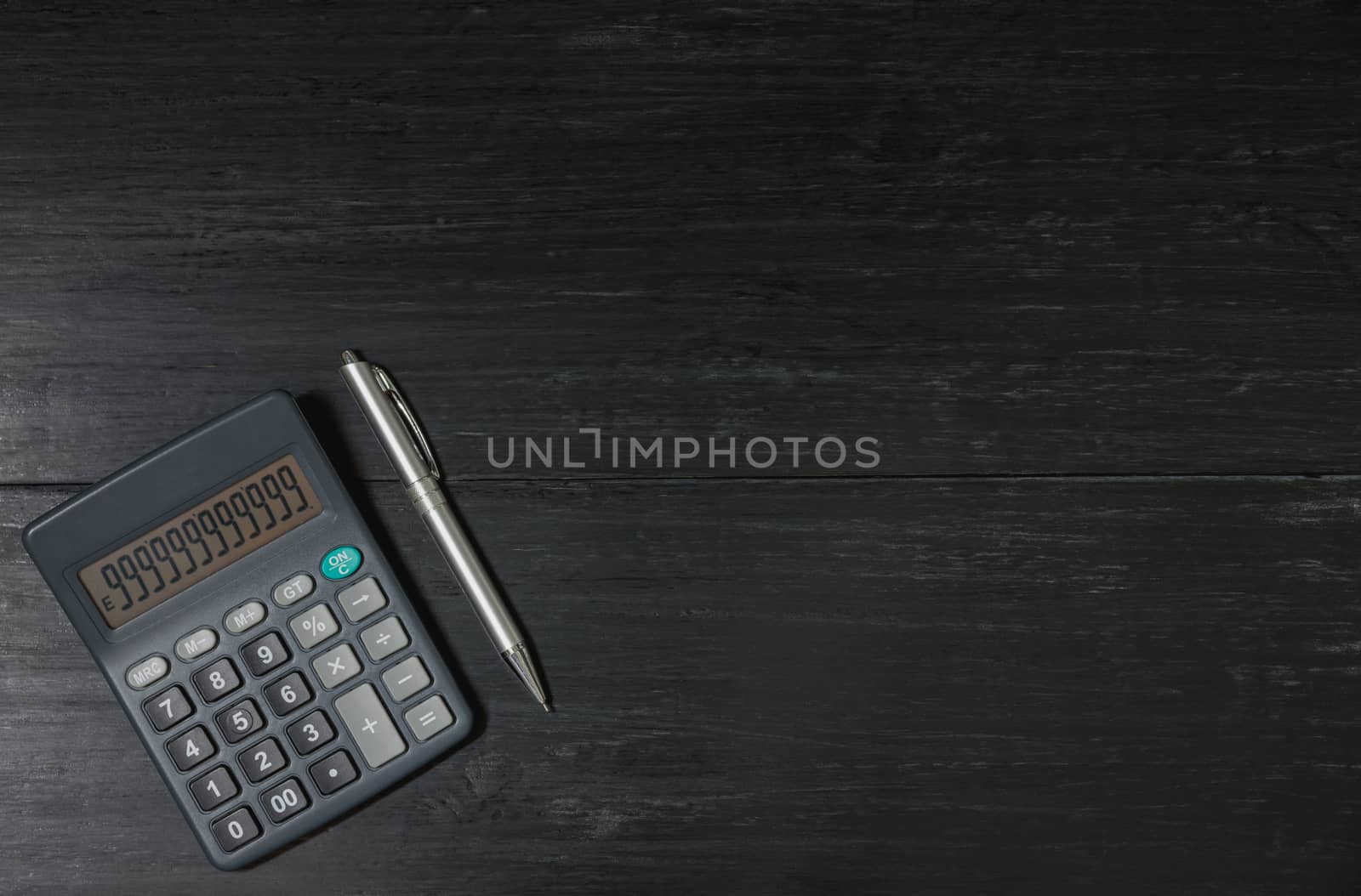 A calculator and pen on wooden background with copy space for insert text.