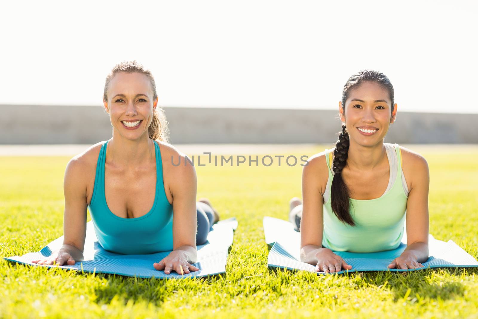 Portrait of smiling sporty women on exercise mats in parkland