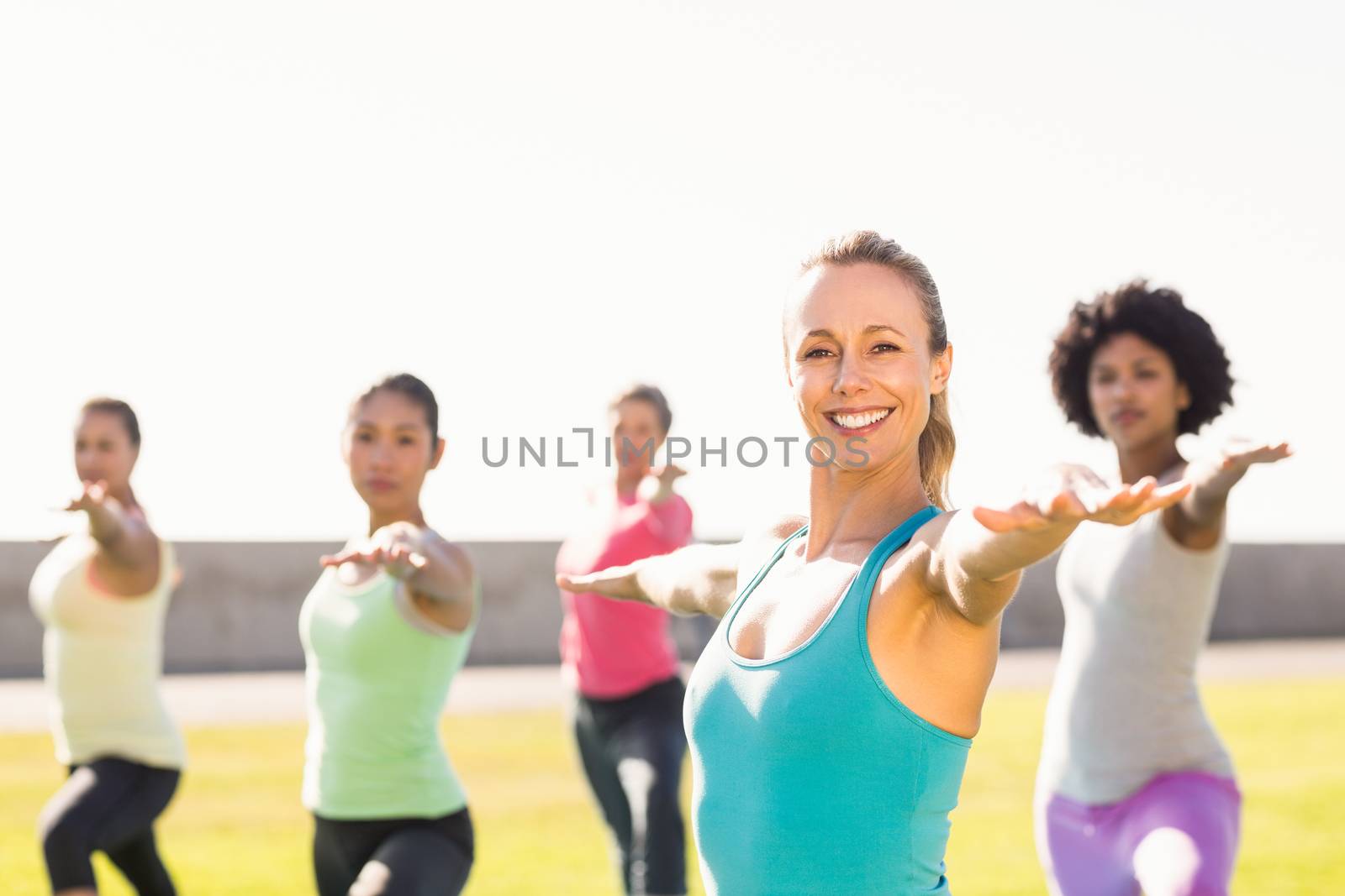 Portrait of smiling sporty blonde doing yoga in yoga class in parkland