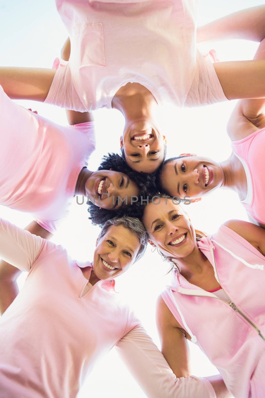 Women wearing pink for breast cancer with arms around by Wavebreakmedia