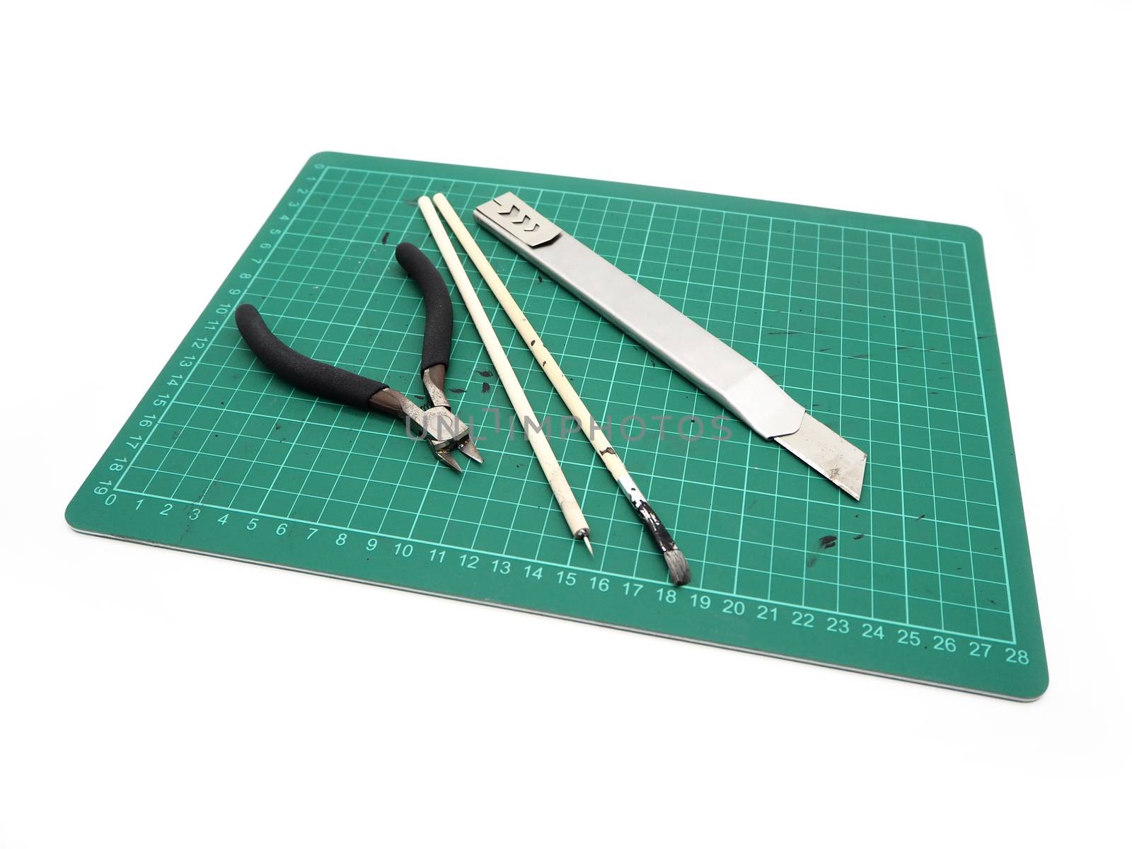 Tools with green cutting mat for model kit isolated on white background.