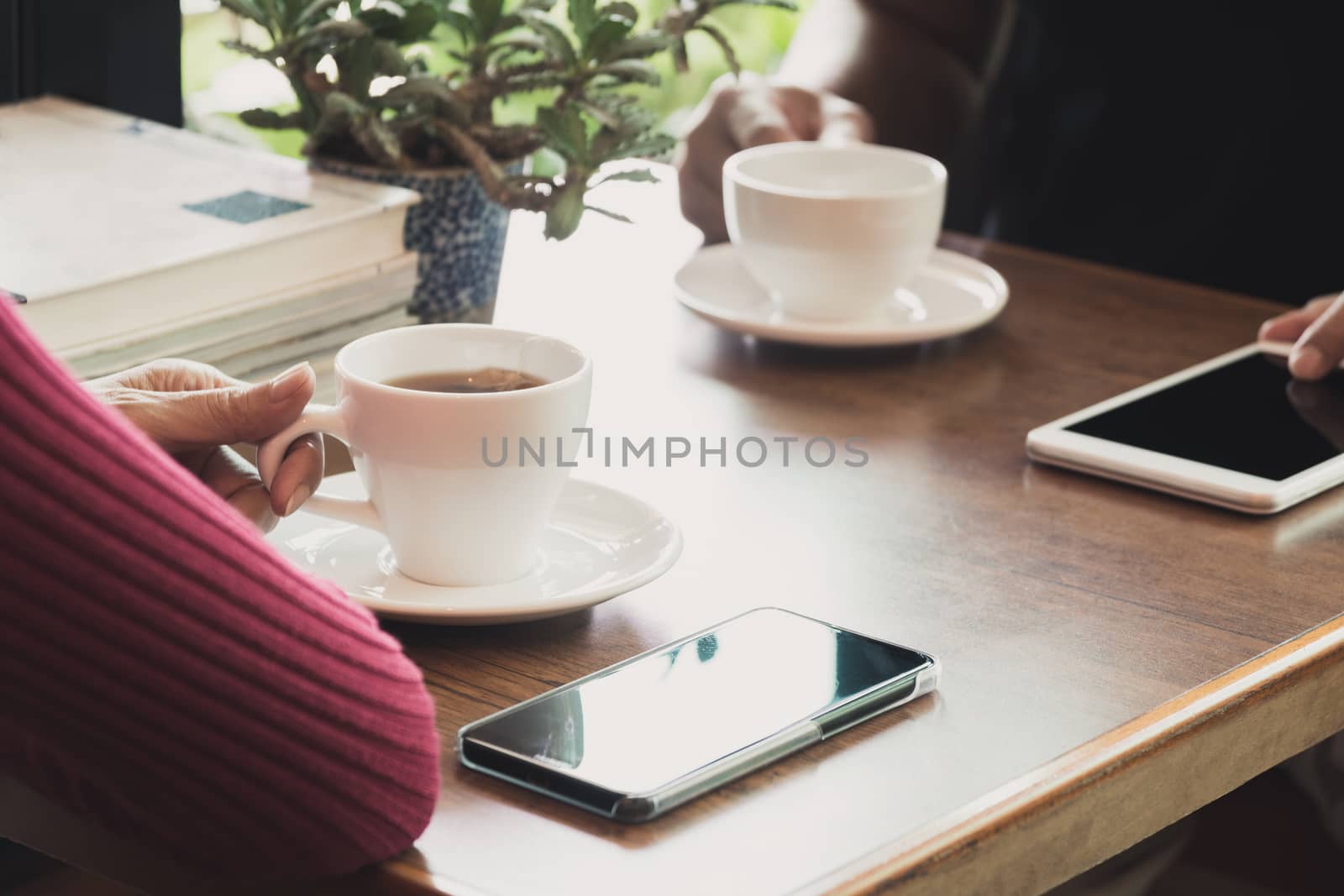 Female's hand holding a tea cup on wooden table.