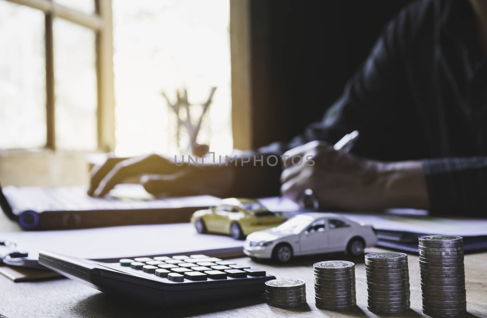 Car insurance and car service. Businessman with stack of coins and toy car, business and financial concept.