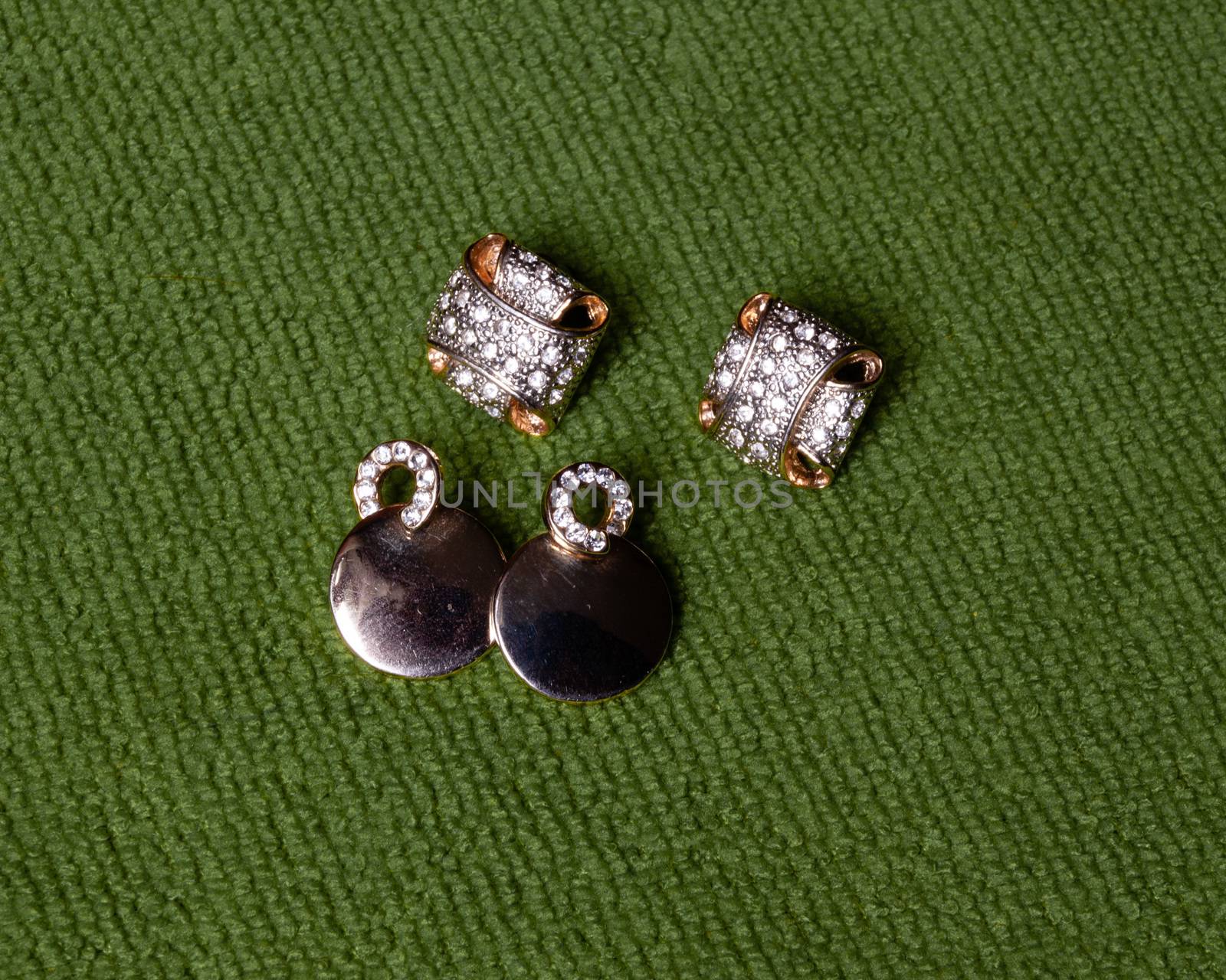 Gold jewelry, earrings lie on a green background