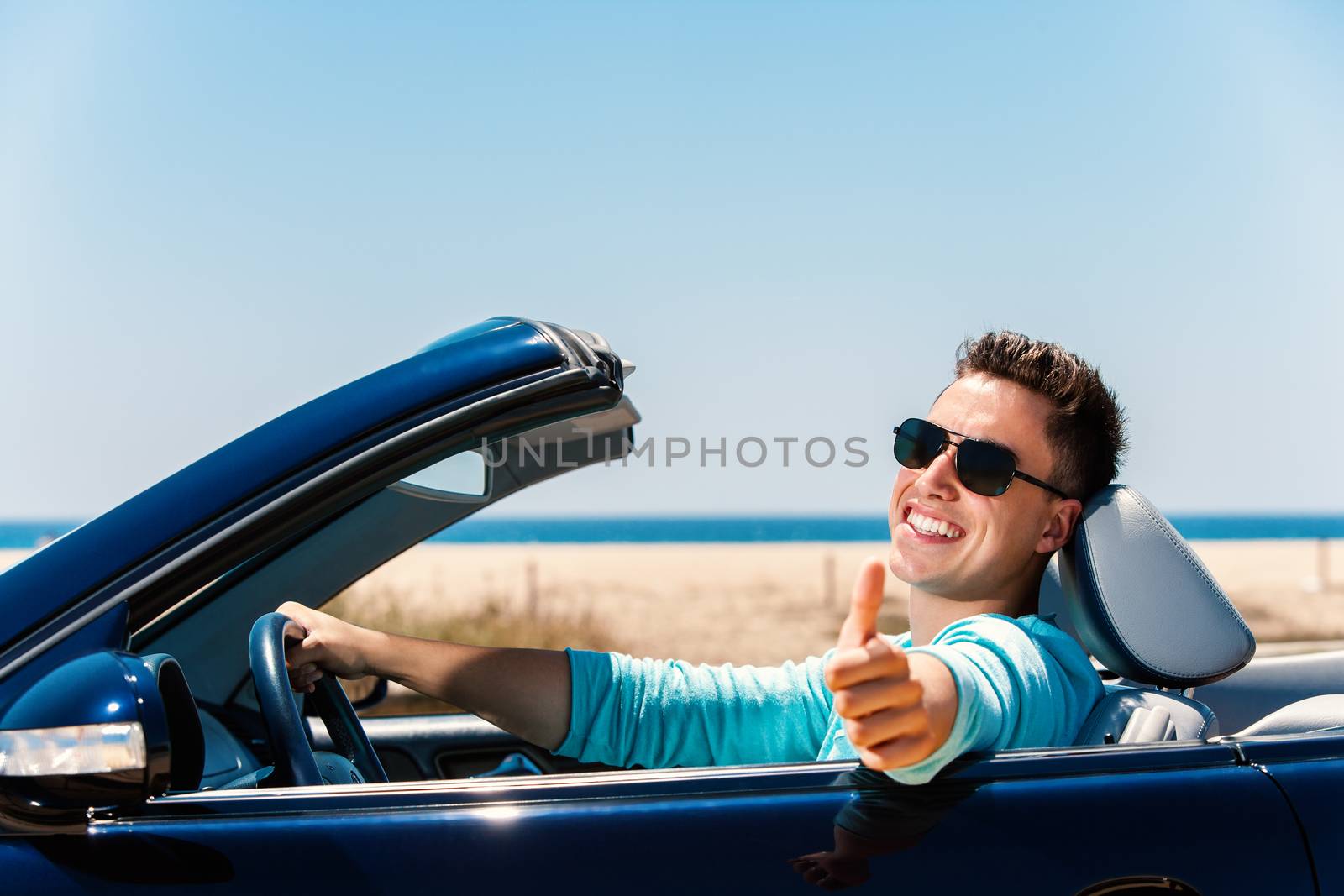 Young man in convertible doing thumbs up. by karelnoppe