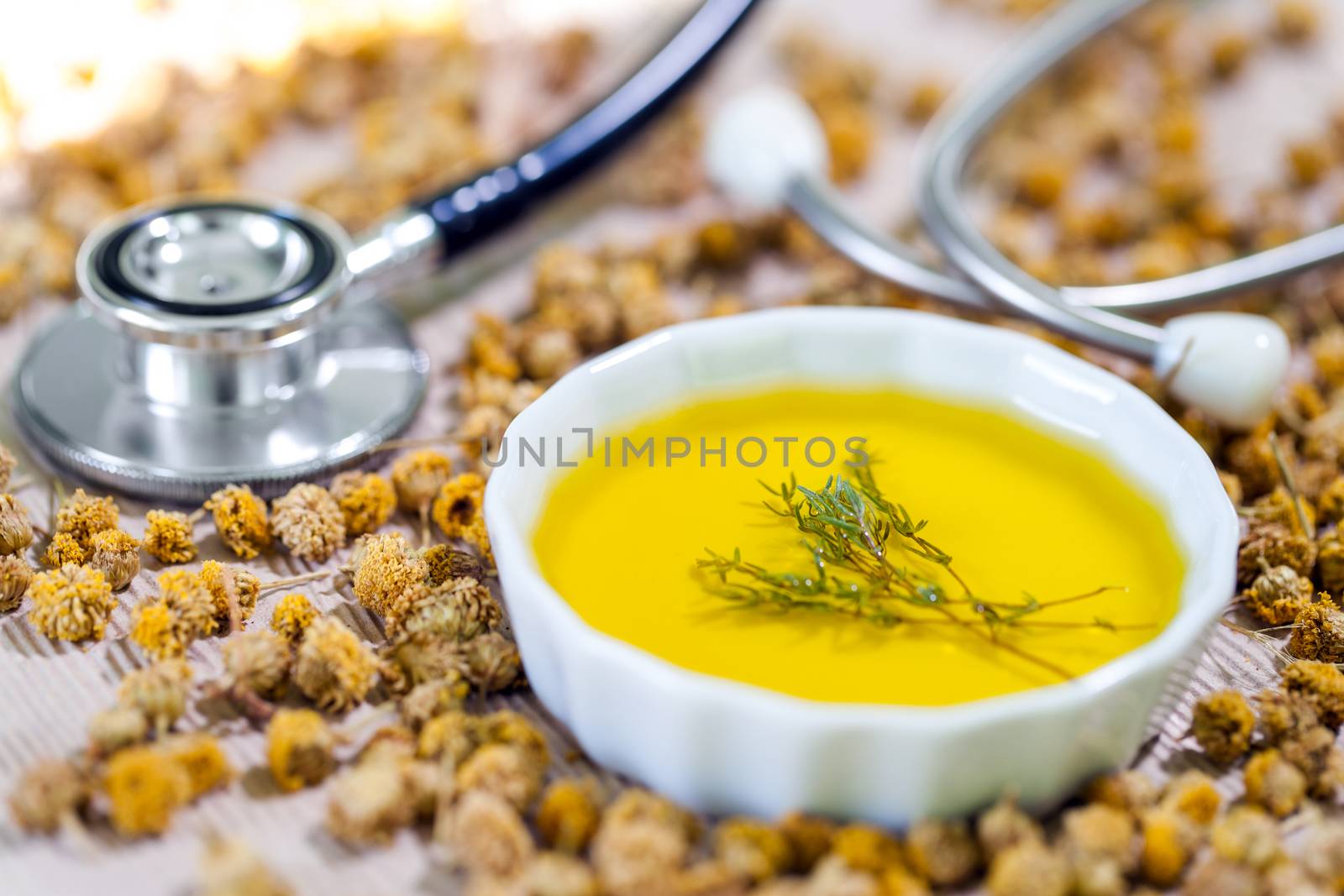 Macro close up of white ceramic bowl with Essential oil and medical stethoscope in background.
