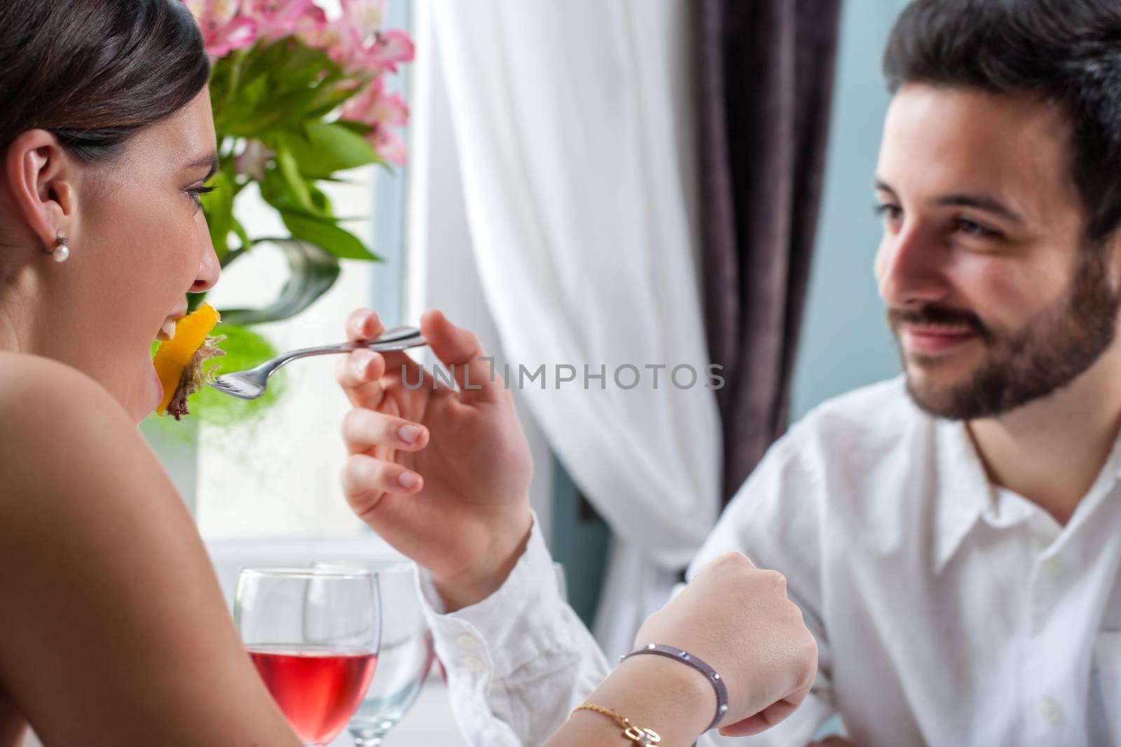 Boyfriend feeding girl at dinner. by karelnoppe