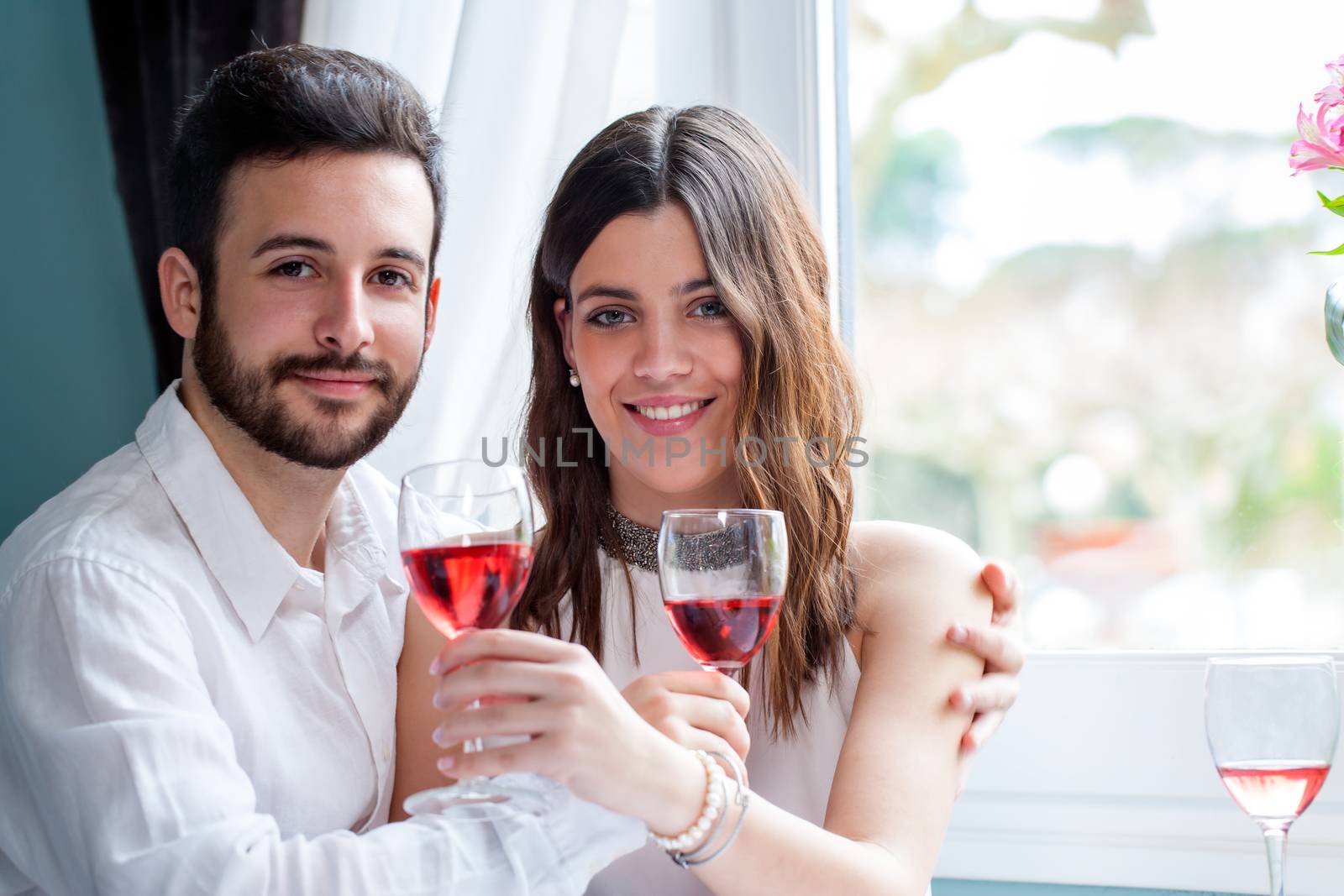 Close up portrait of young couple holding wine glasses on date in restaurant.