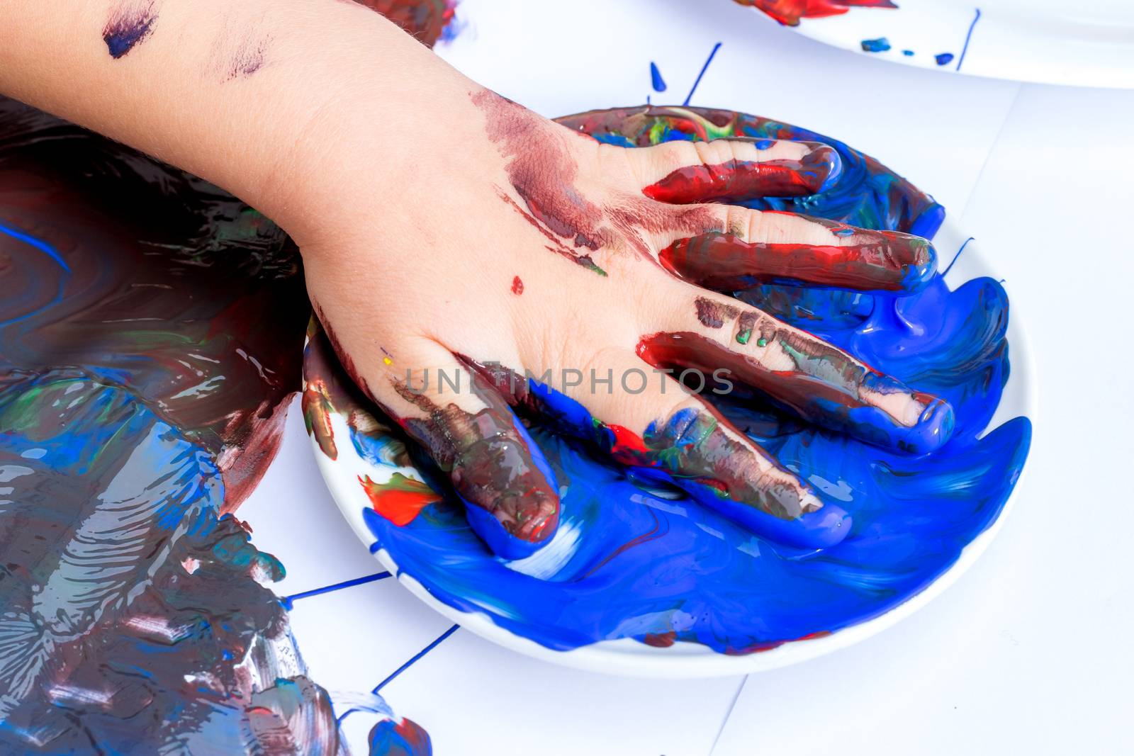 Macro close up of infants hand soaked in blue paint ready for painting.