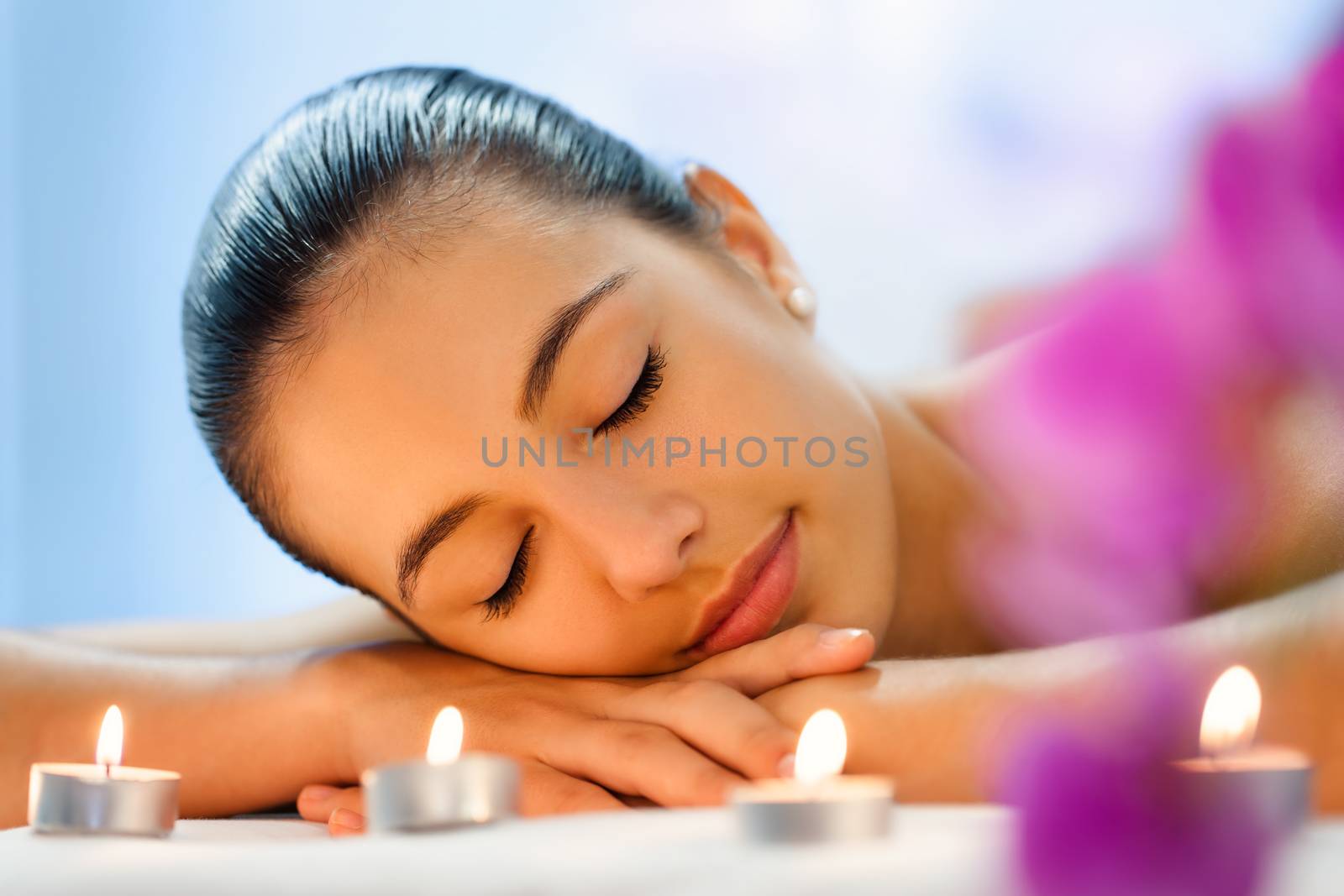 Young woman relaxing in dimmed candle light after massage. by karelnoppe