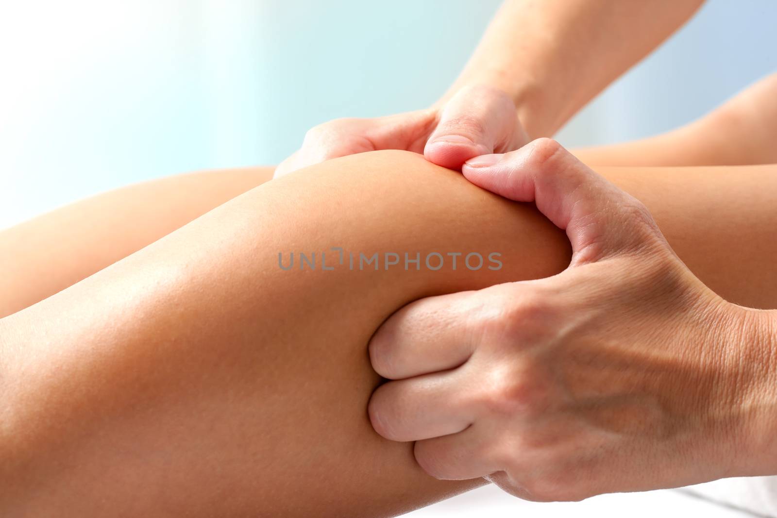 Macro close up of hands doing manipulative healing massage on female calf muscle.