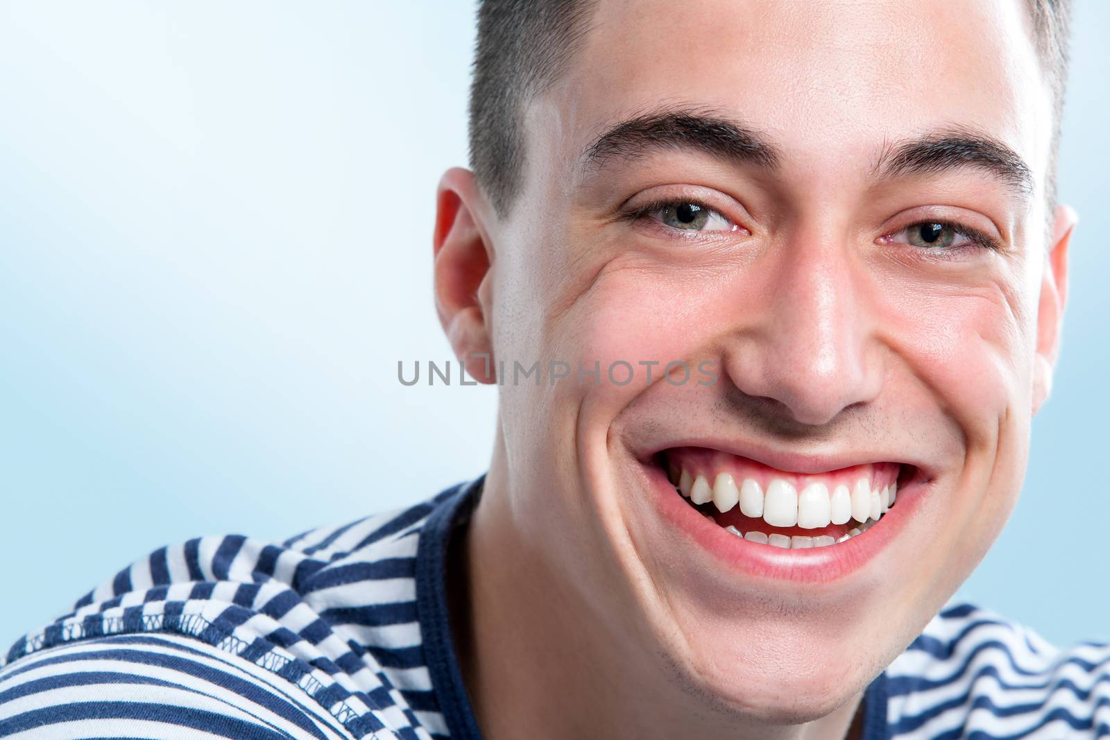 Extreme close up face shot of Young man with charming and healthy toothy smile. 