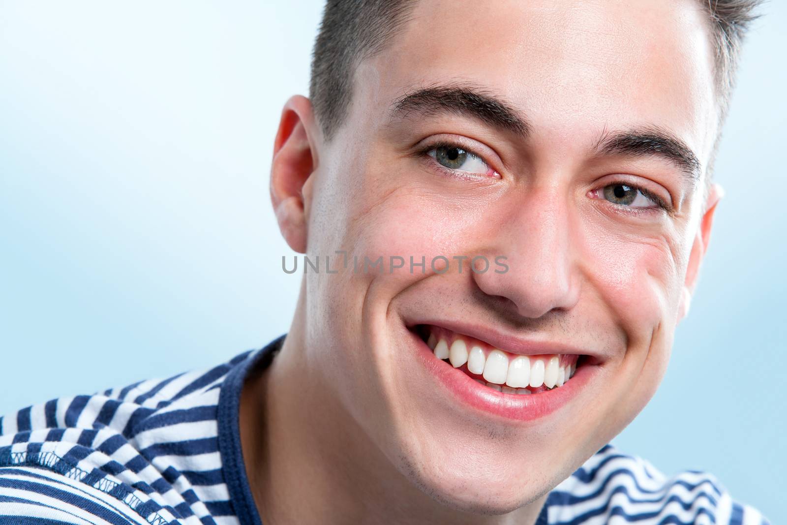 Macro face portrait of Handsome young man with healthy teeth looking aside.