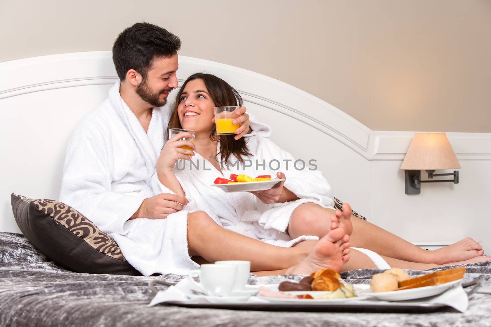 Close up portrait of Young couple on honeymoon in hotel room. Couple enjoying room service with breakfast tray.