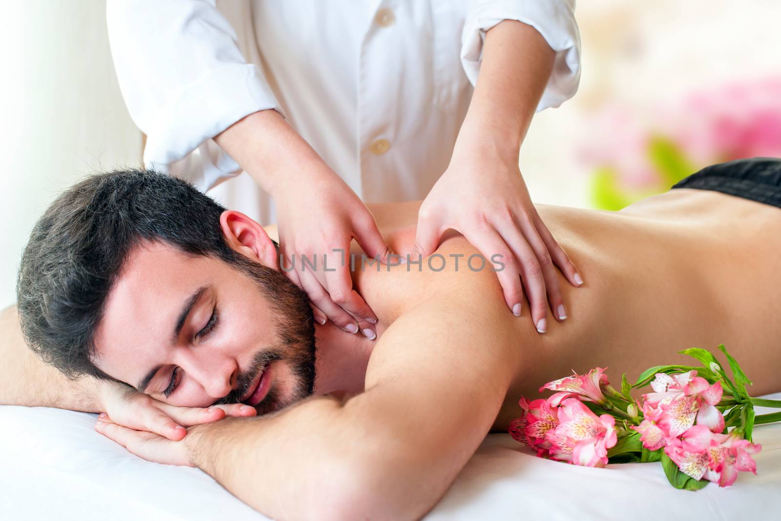 Close up of therapist hands doing upper back and shoulder massage on young man.