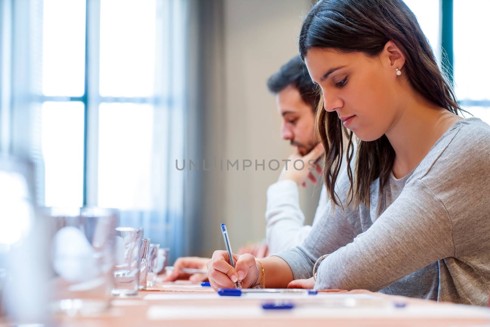 Portrait of young students at work in Hotel conference room. Young woman writing with pen at desk.