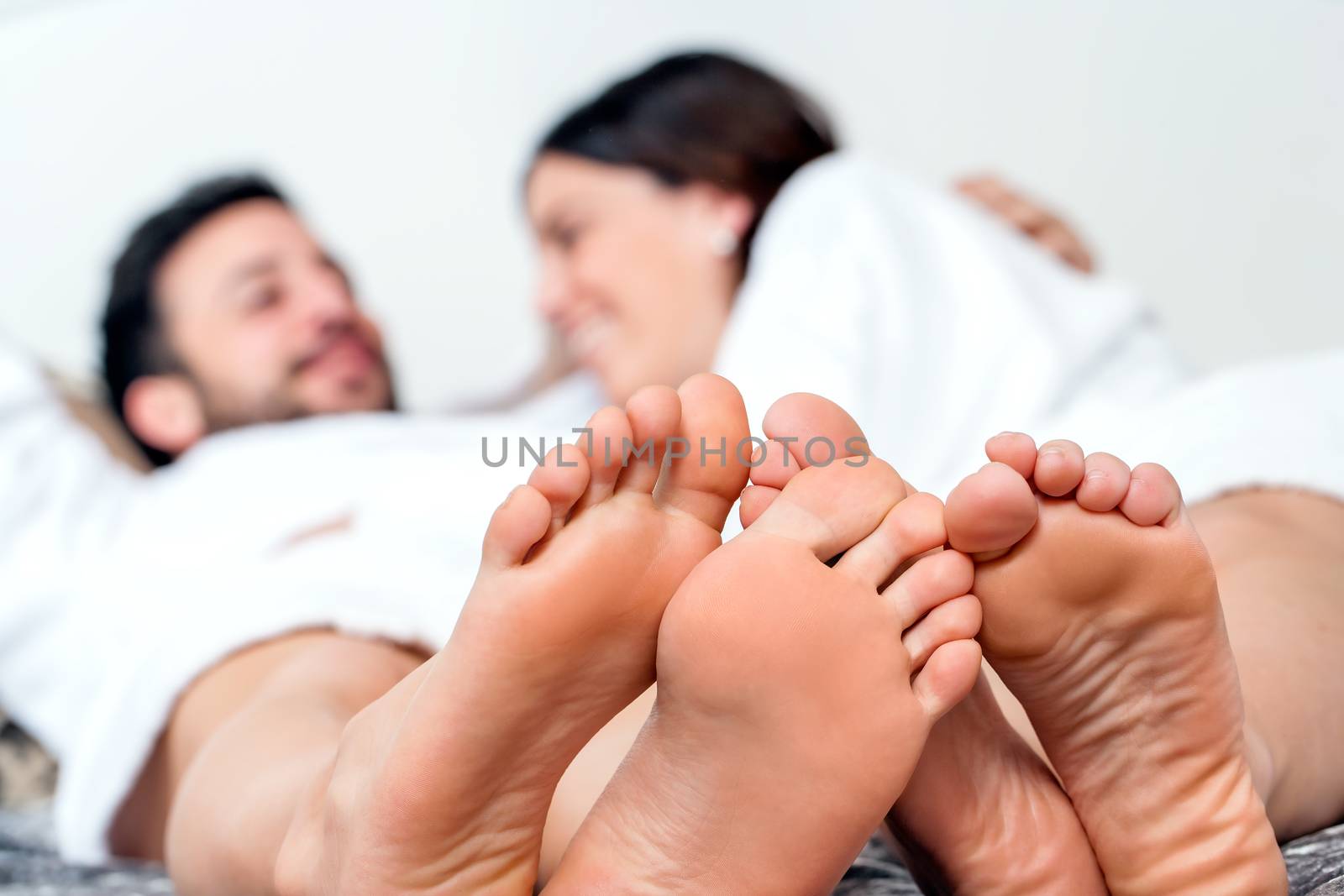 Close up detail of human feet together with out of focus laughing couple in background.