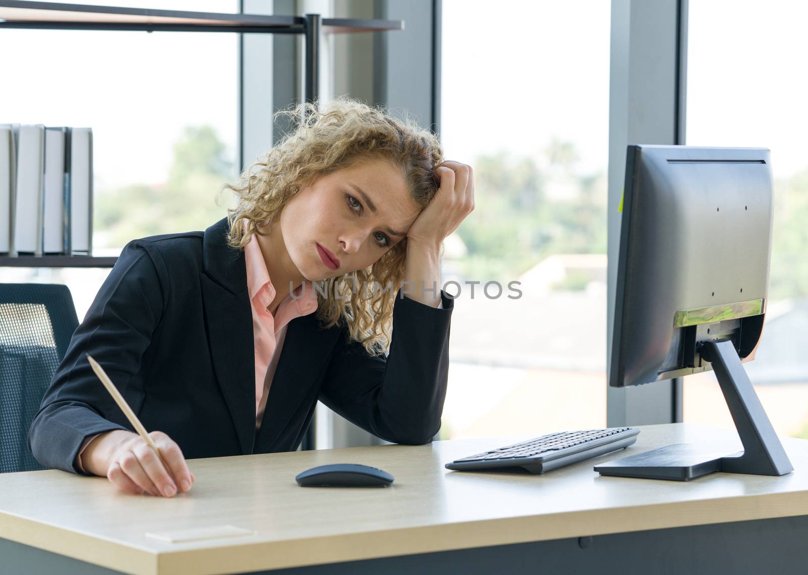 Morning work atmosphere In a modern office. Ukrainian employee hold the head with one hand at her desk. After receiving the assignments work