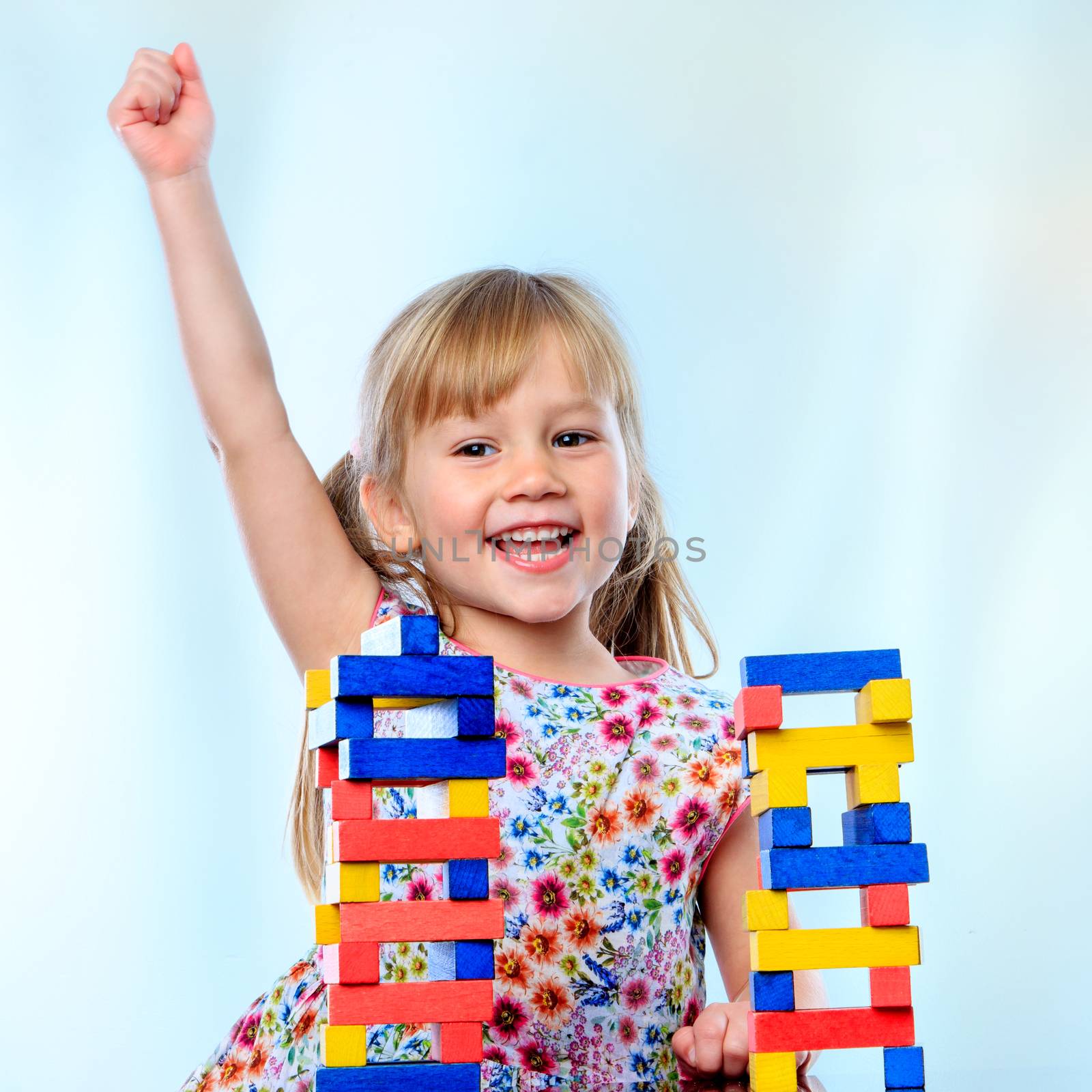 Close up portrait of excited little girl in front of educational wooden block game.