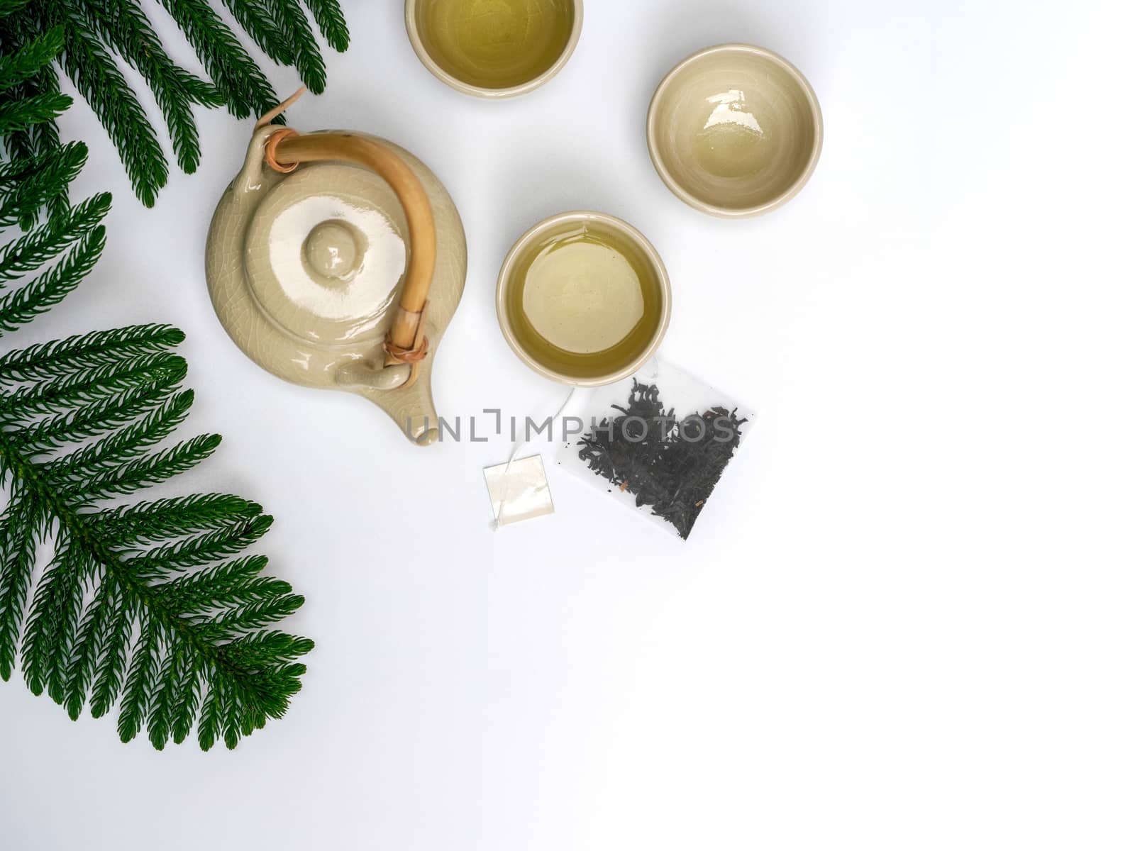 A set of ceramic teapot with wood handle on table. Teabag with white label.