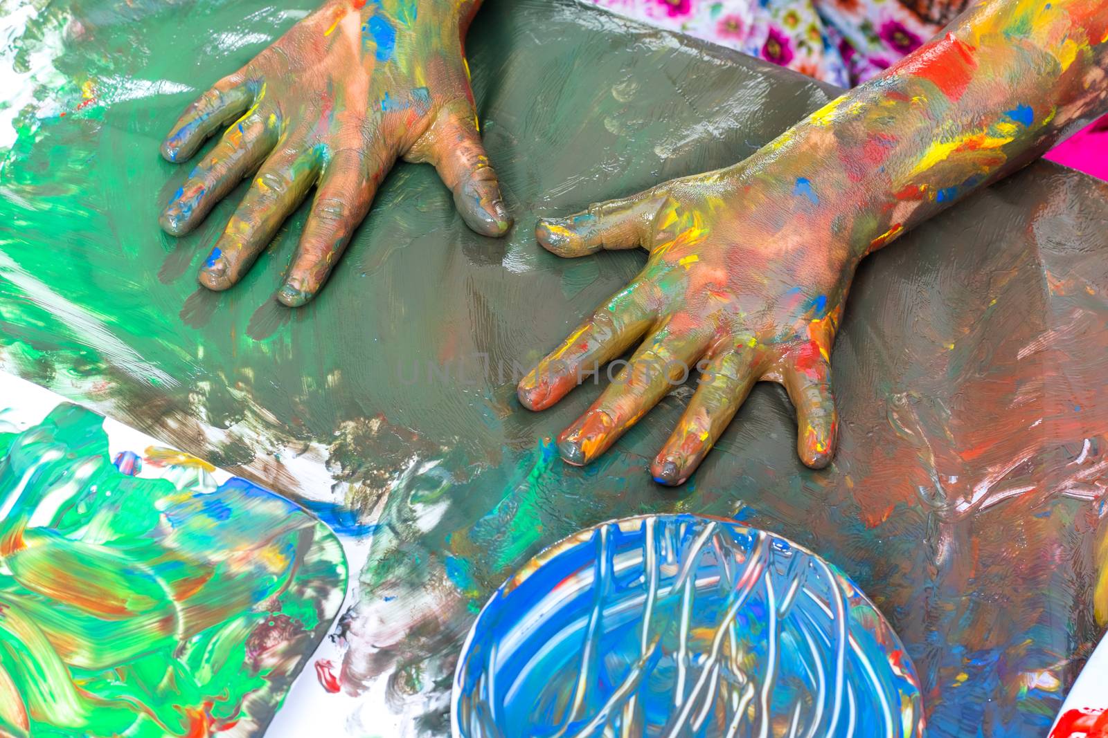 Close up Top view of child’s hands painting at table. Abstract painting with hands covered in paint.