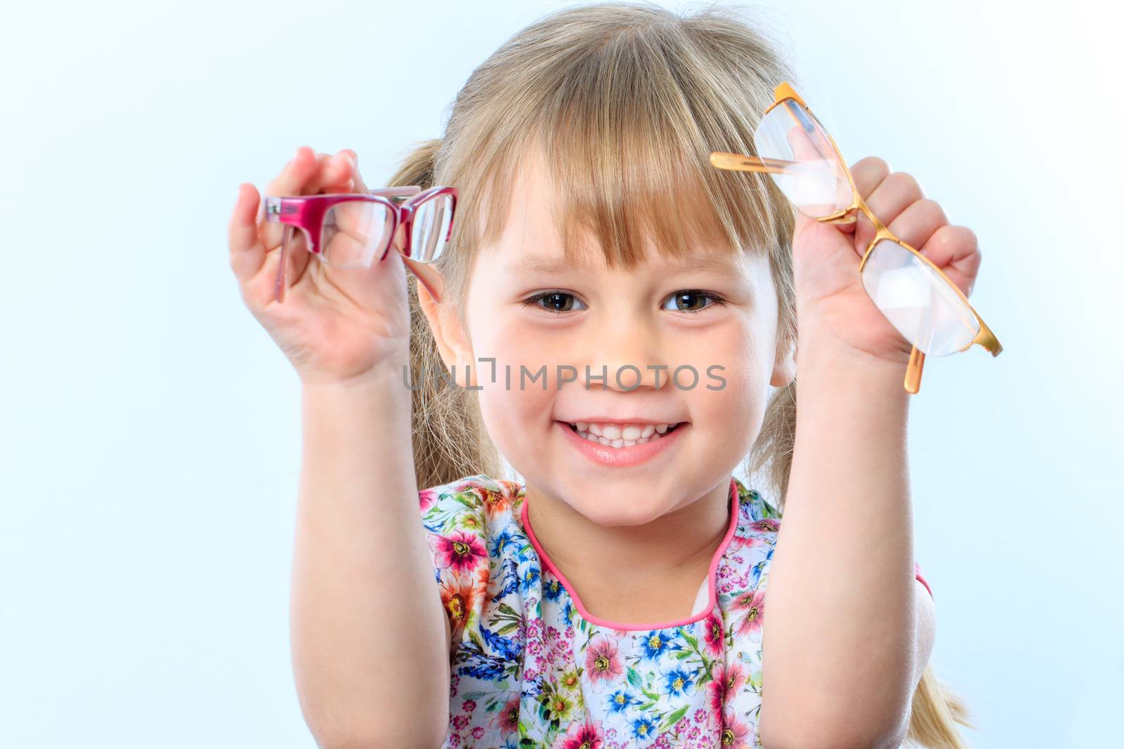 Close up portrait of infant holding two glasses at eye test.