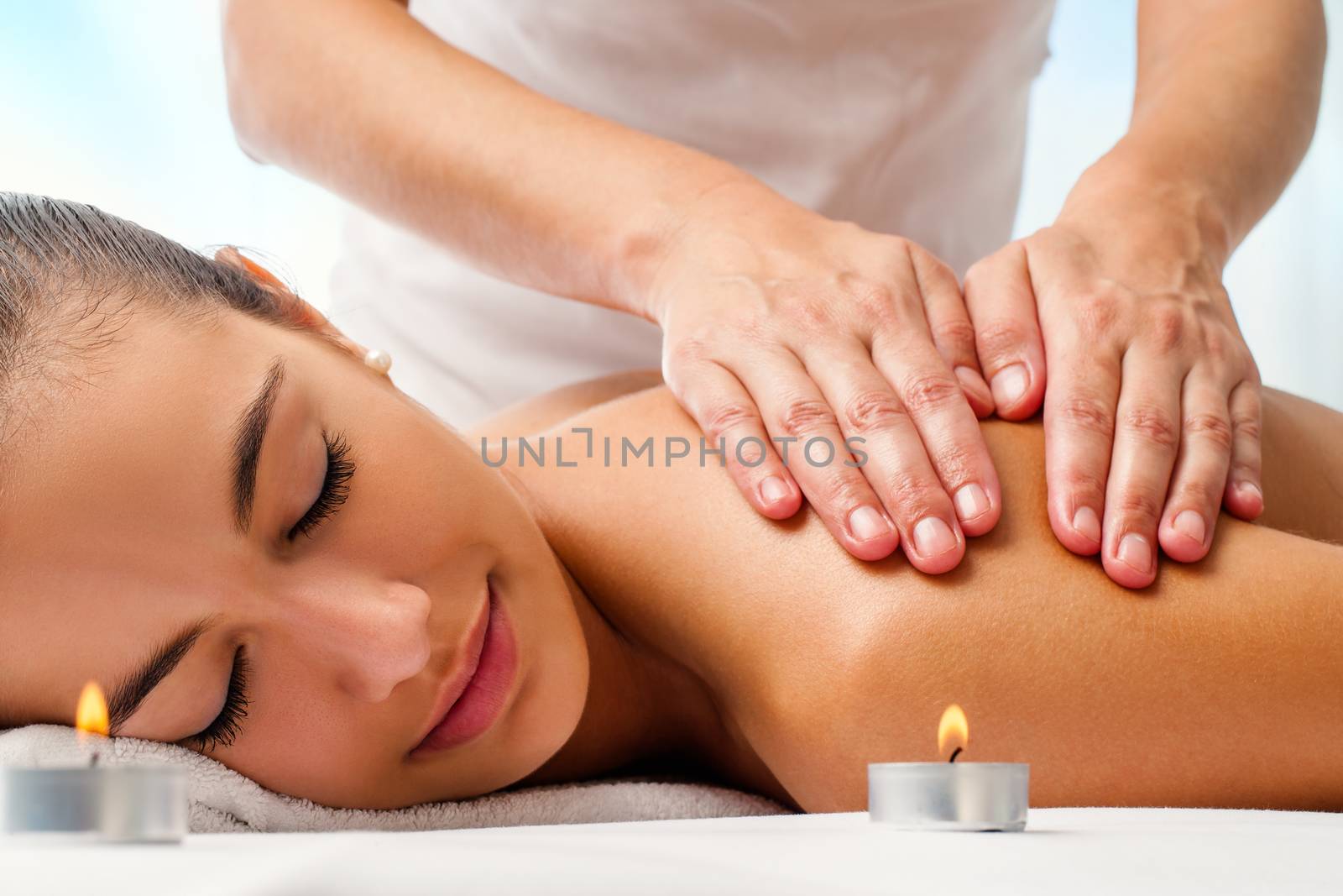 Close up portrait of attractive woman enjoying relaxing massage.Therapist doing manipulative treatment on shoulders.