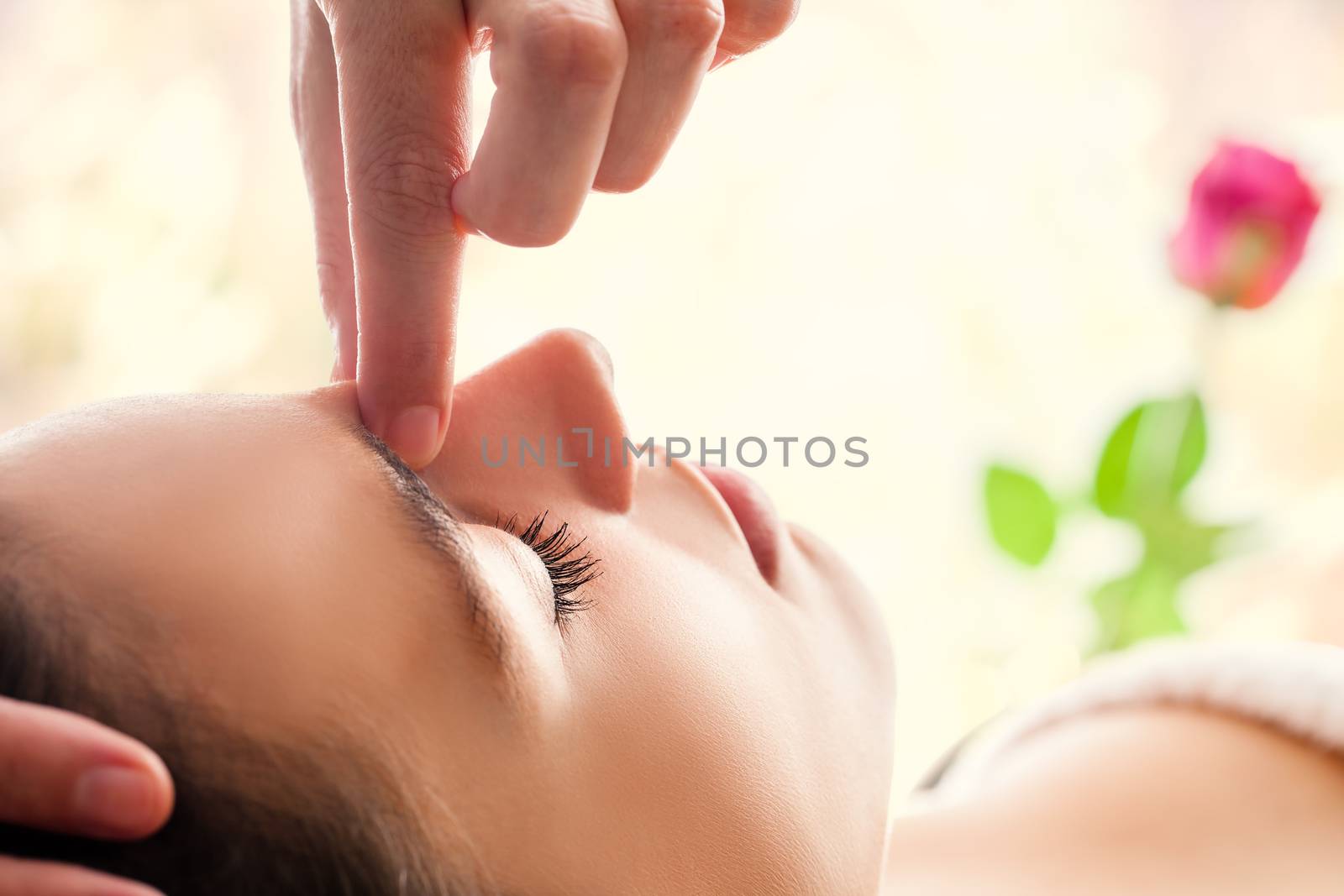  Macro close up of  relaxing facial massage. Therapist applying pressure with fingers between eyes.