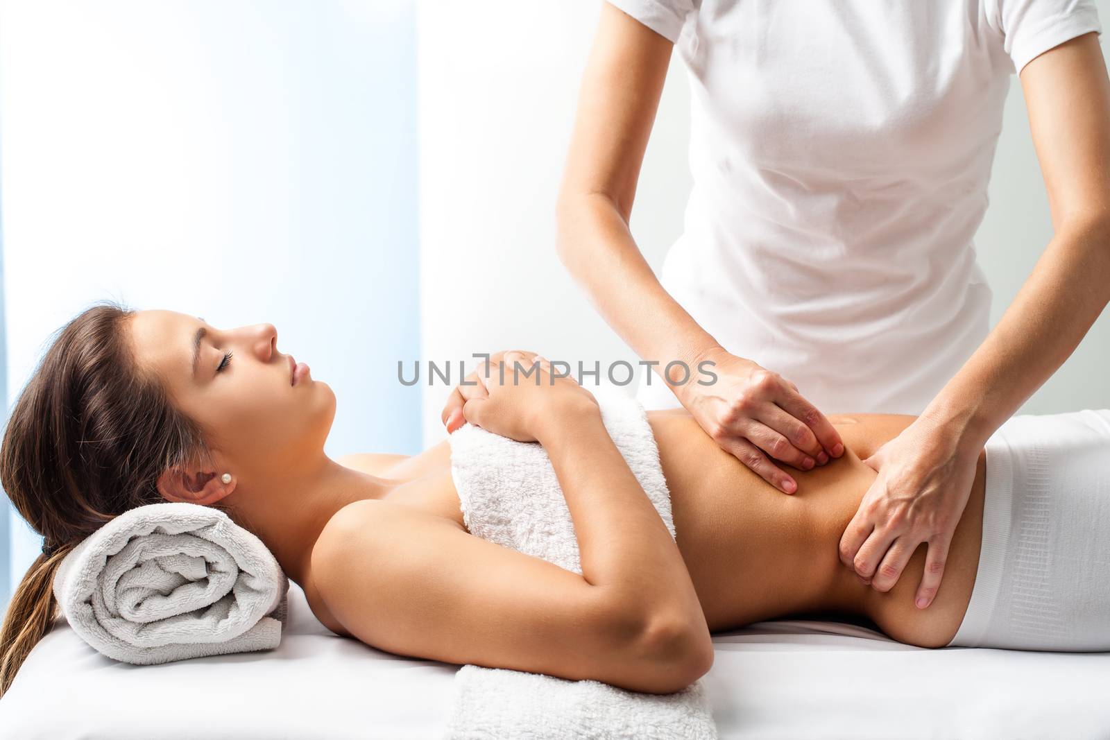 Close up of osteopath doing manipulative massage on female abdomen.
