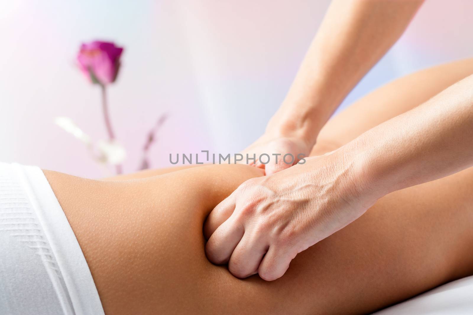 Close up of therapist hands massaging female hamstrings on leg.