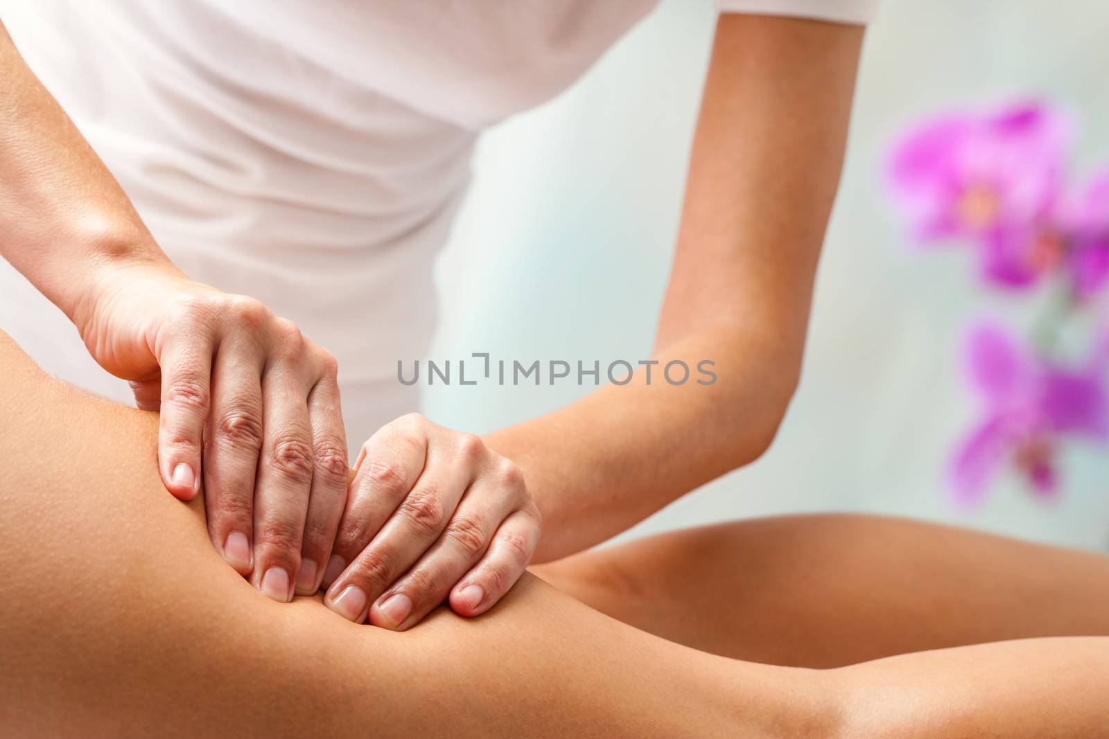 Therapist doing rehabilitation massage with hands on female hamstrings.