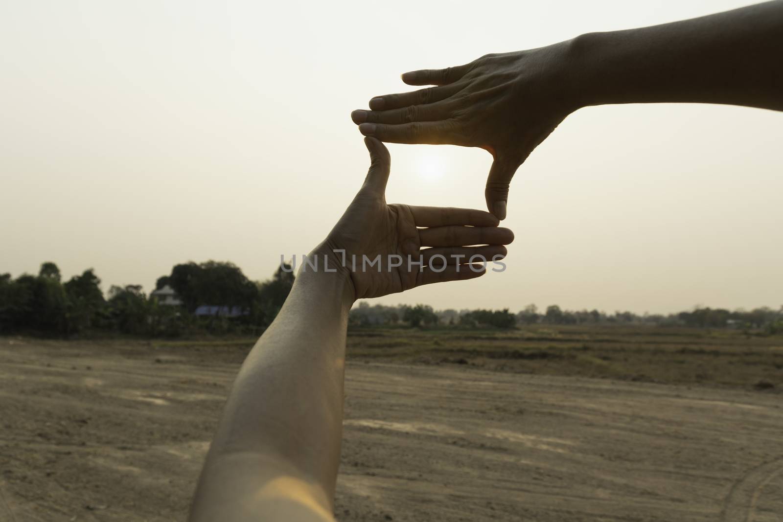 Hands making frame with sunset. Close up of woman hands making frame gesture.