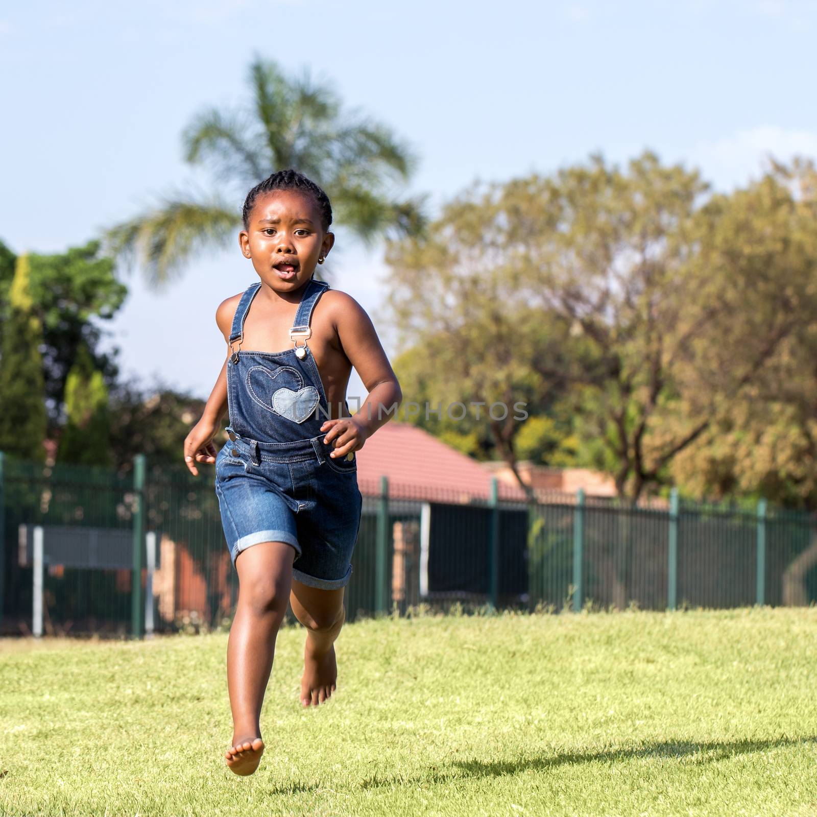 Close up action portrait of little african kid running in park.