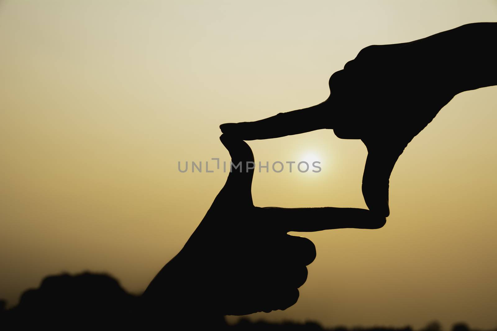 Hands making frame with sunset. Close up of woman hands making frame gesture.
