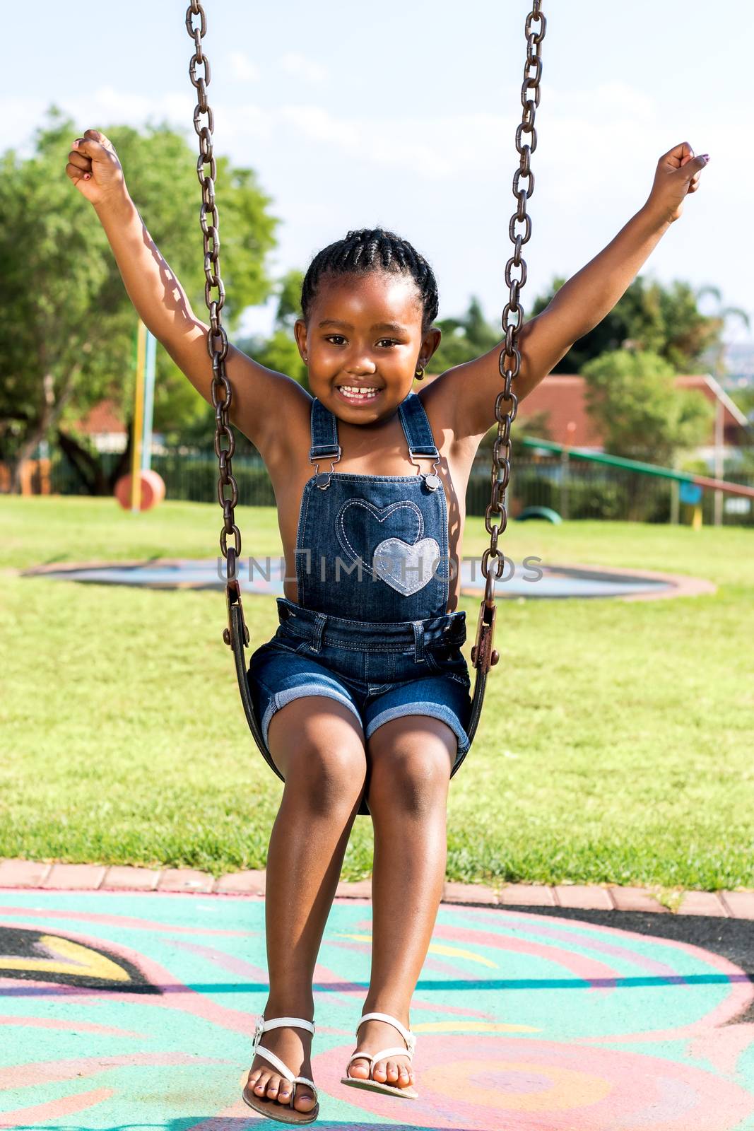 Full length portrait of cute Little african child swinging in park.