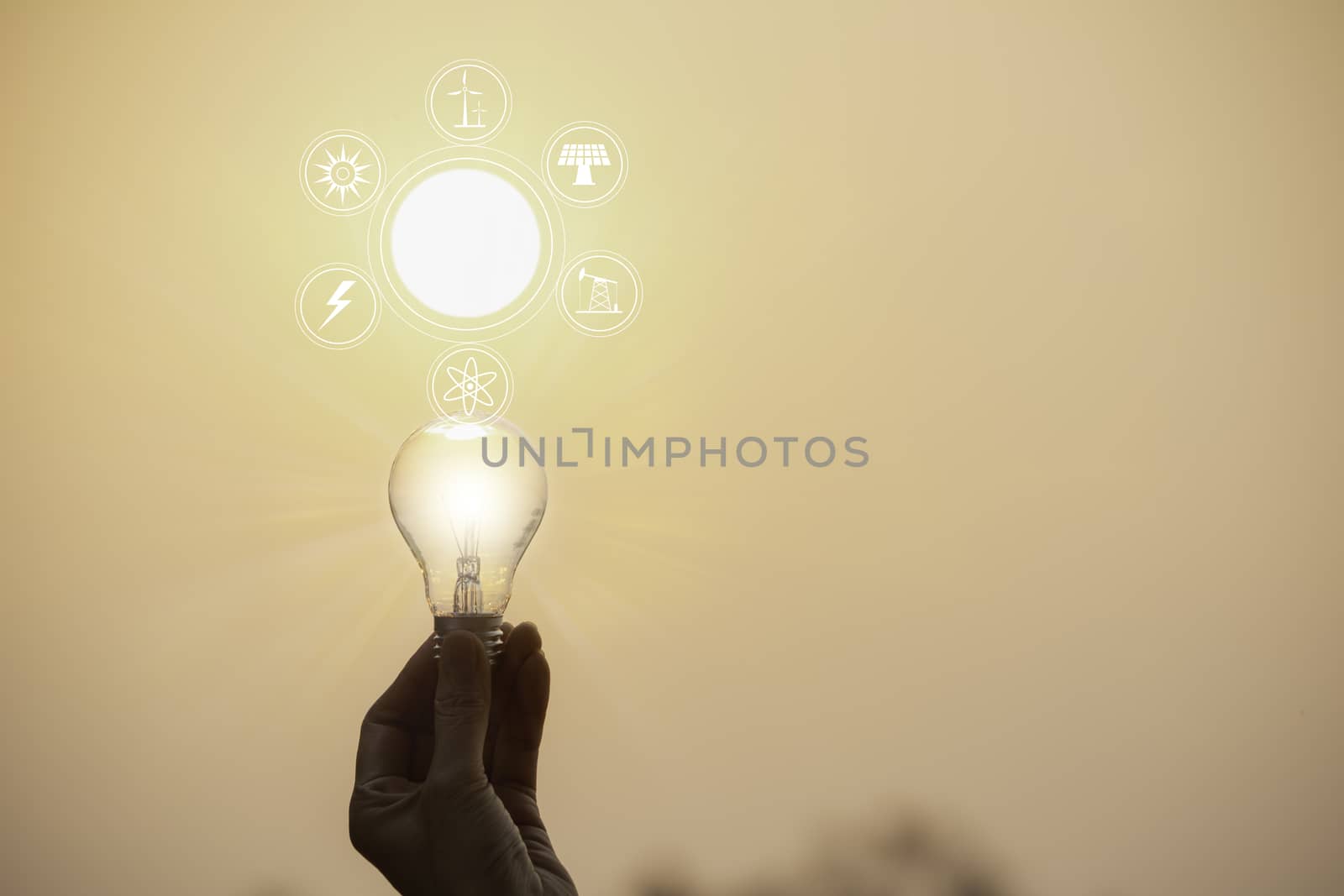 Hand hold a light bulb on sunset background for saving energy and creative concept.