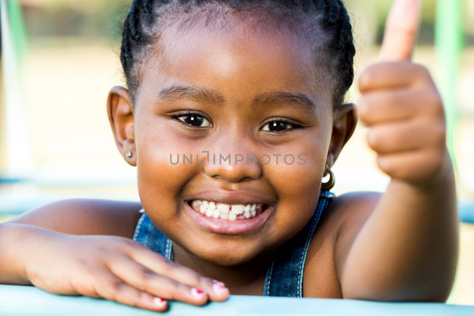 Face shot of african girl doing thumbs up outdoors. by karelnoppe
