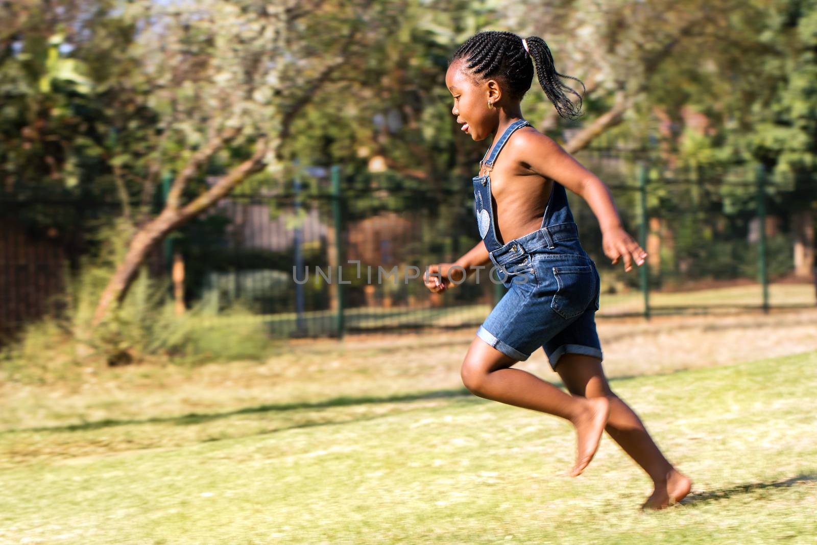 Side view of african kid running in park. by karelnoppe