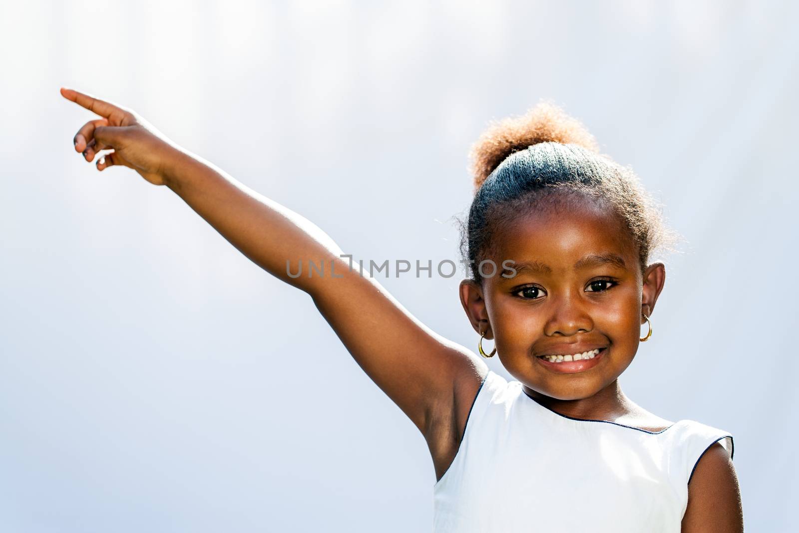 African girl pointing at corner with finger. by karelnoppe