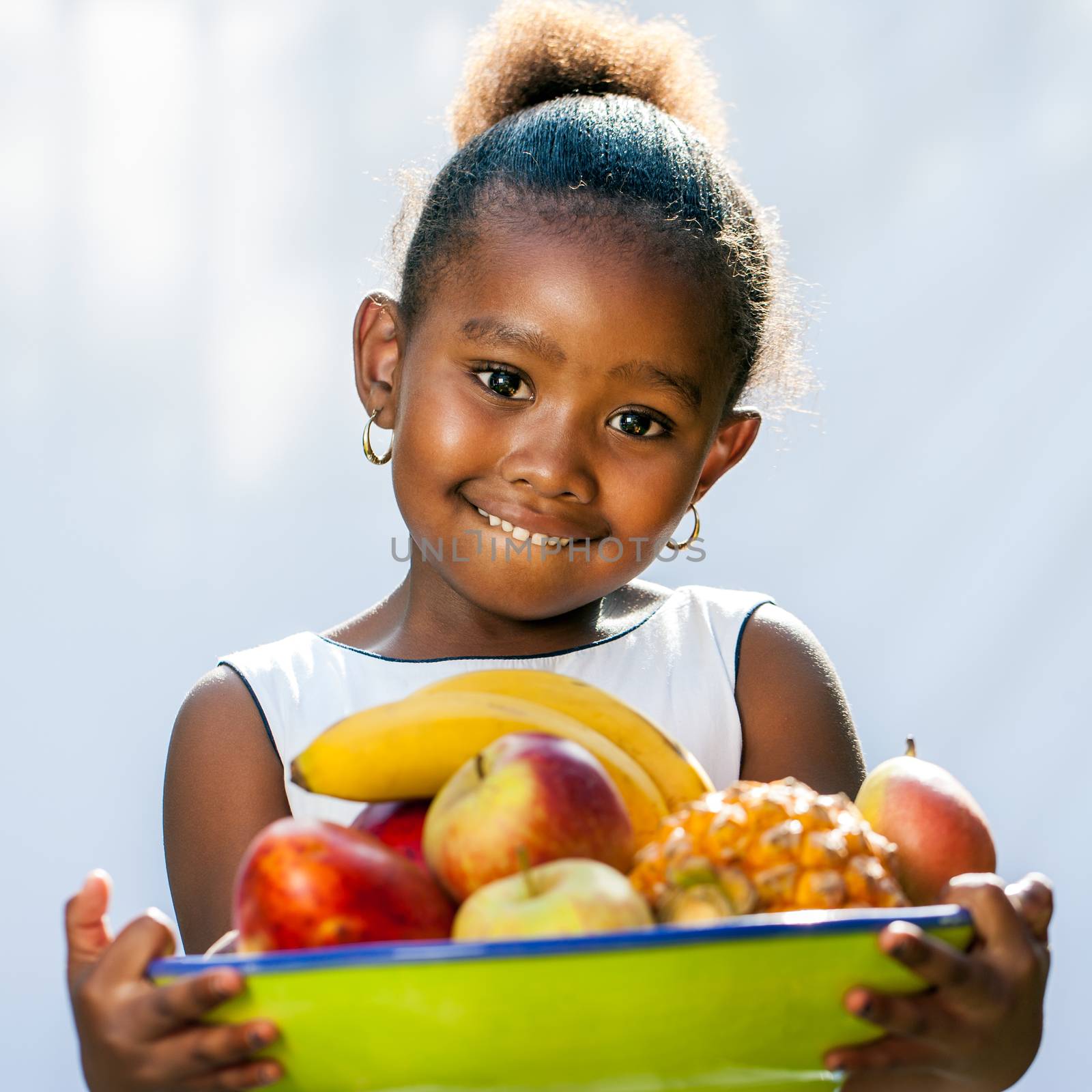 Close up portrait of cute African girl holding fruit bowl.Isolated against light background.