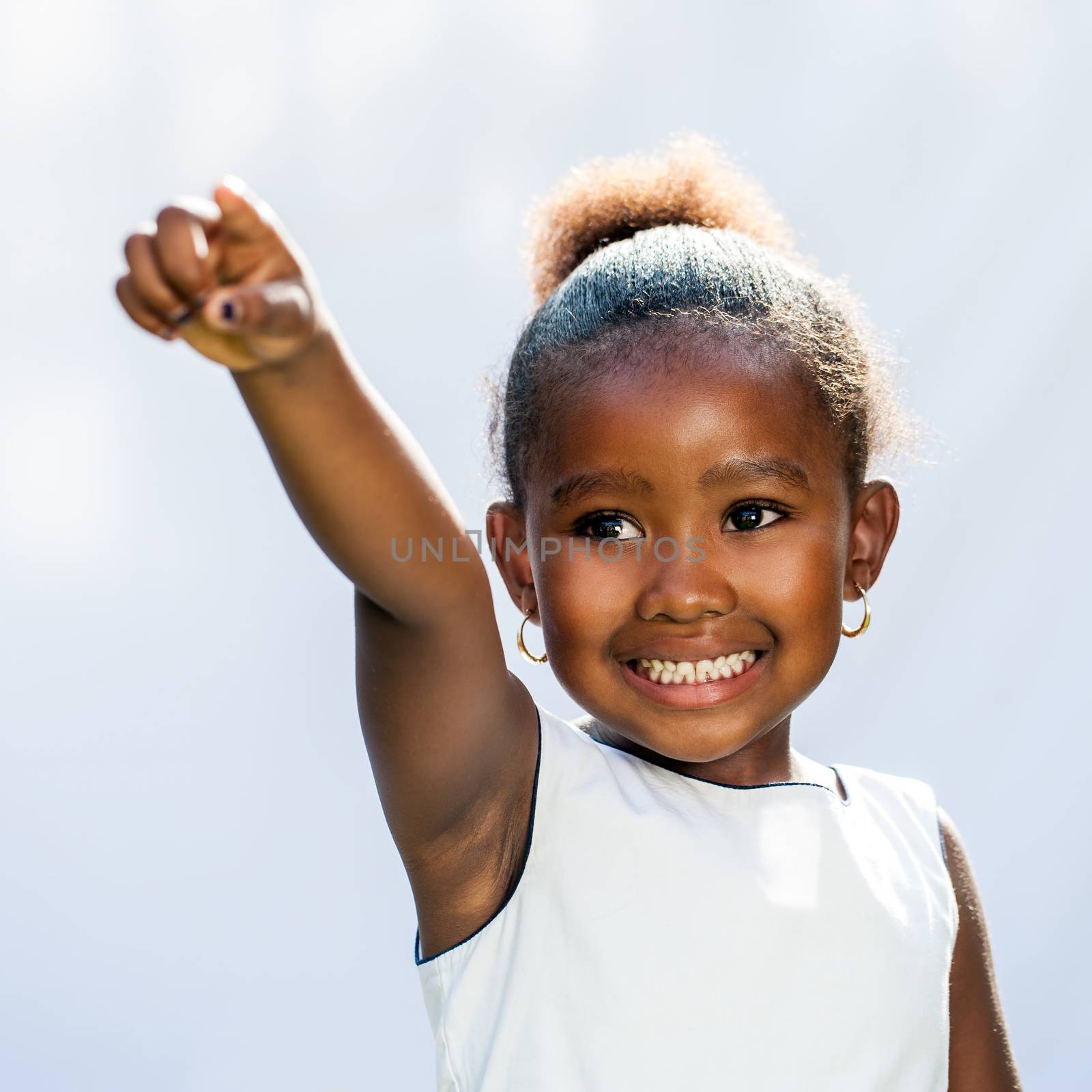 Portrait of small African girl pointing with finger into distance.Isolated against light background.