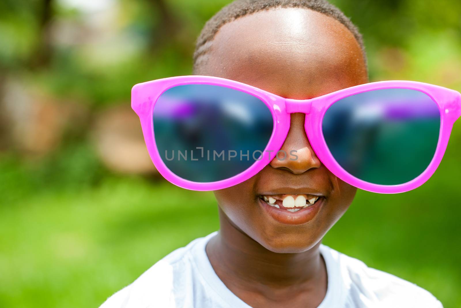 African boy wearing fun extra large sun glasses. by karelnoppe