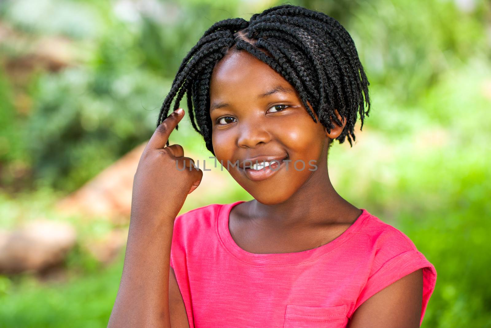 Close up portrait of Cute African girl showing braided hair outdoors in park.