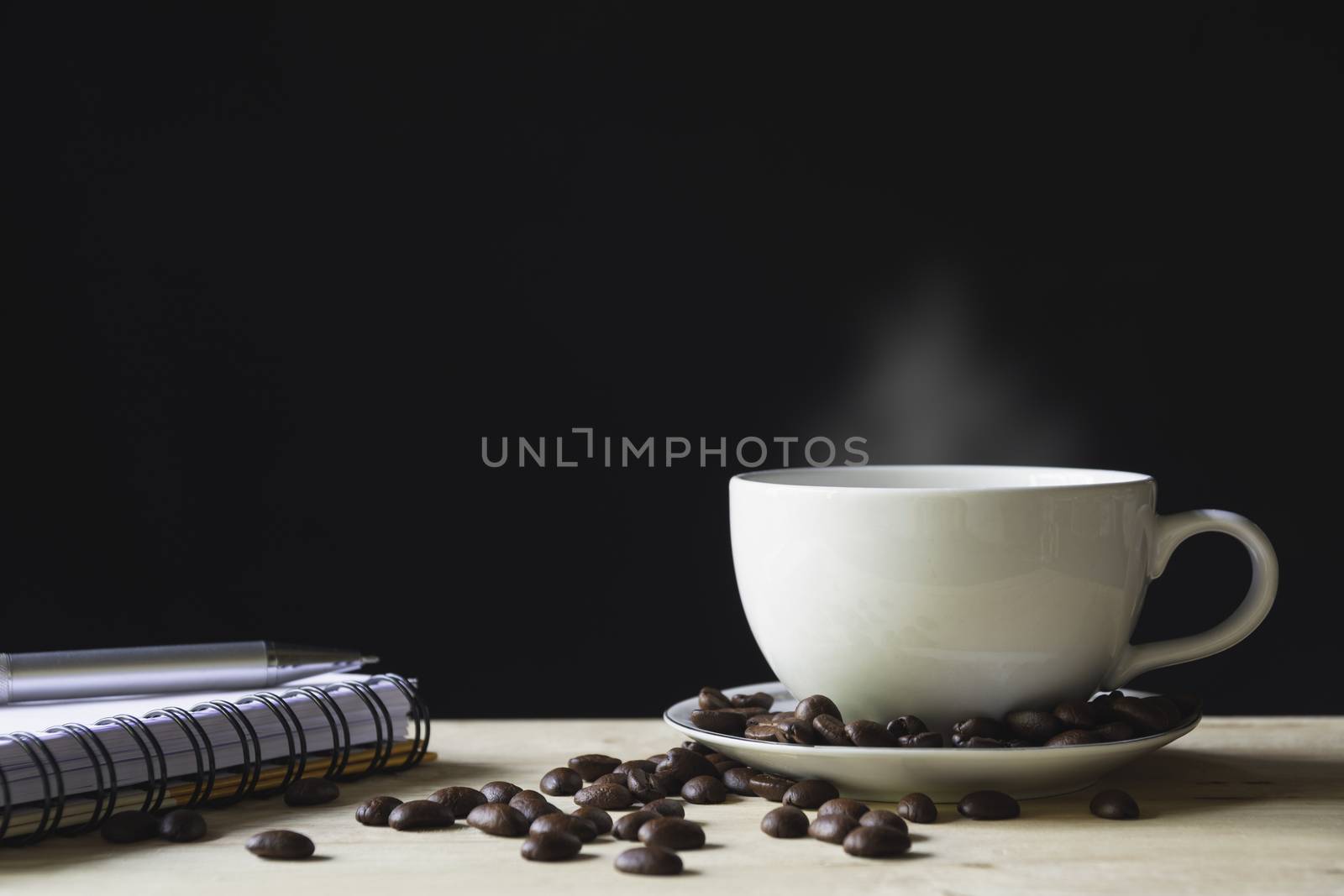 A cup of coffee with coffee beans over wooden table with copy space for food and drink concept.