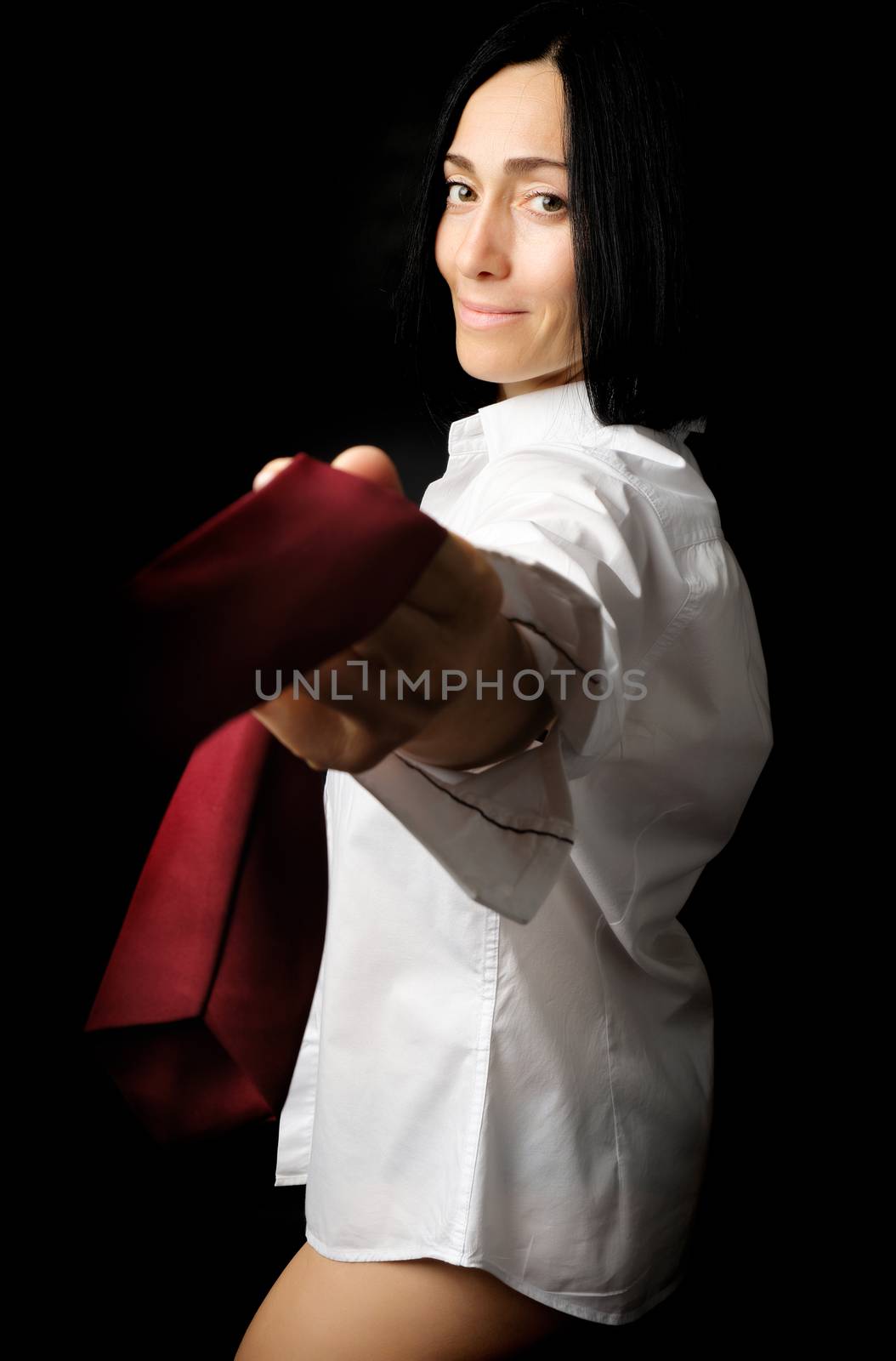 young woman with black hair and a Caucasian appearance is dressed in a white men's shirt and pulls a red tie over herself, low key