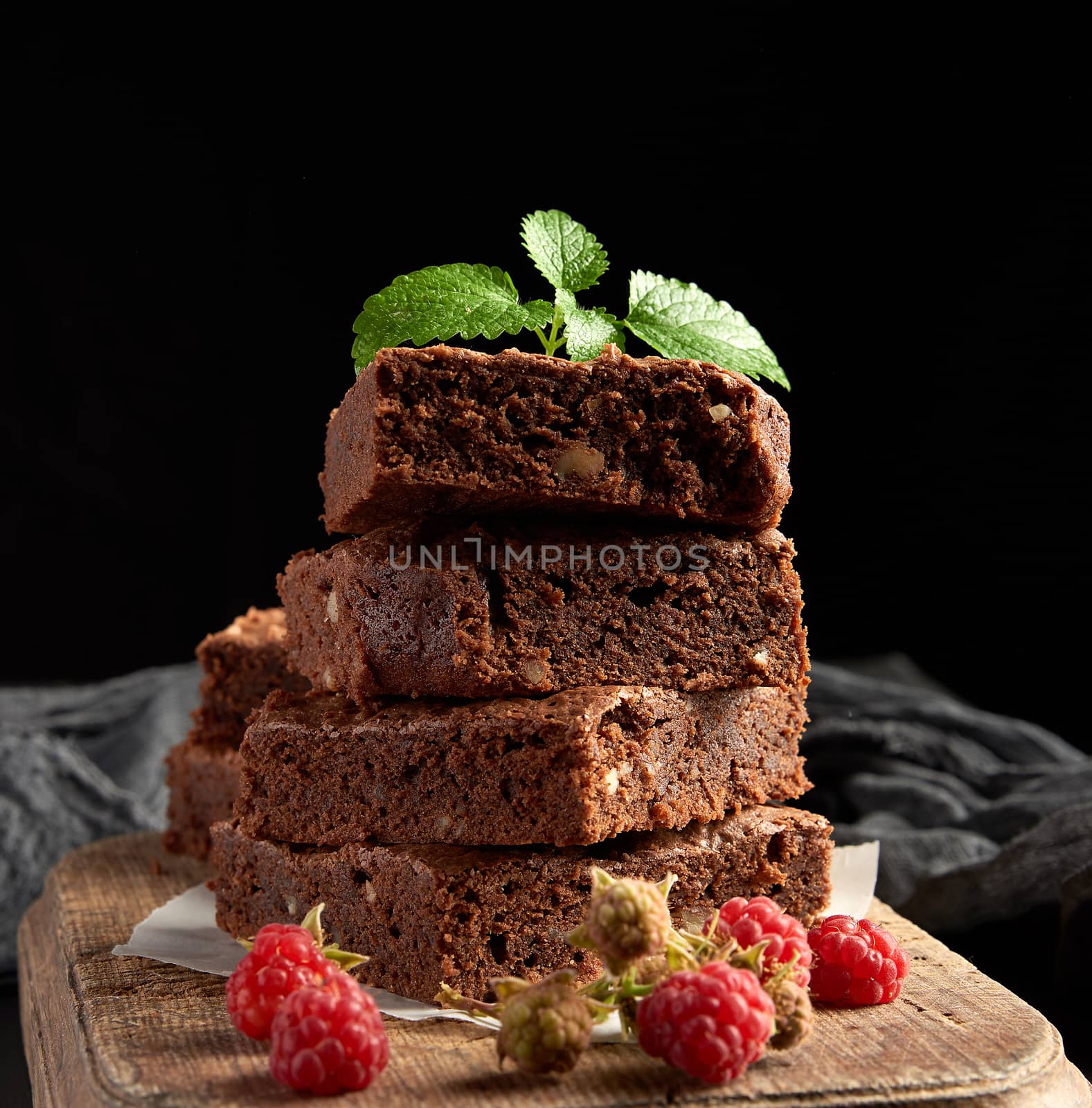 stack of baked square pieces of chocolate brownie cake on brown  by ndanko